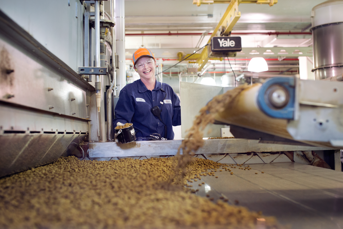 Industrial worker monitoring grain processing equipment in a manufacturing facility.