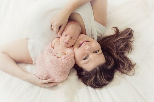 Overhead view of parent and newborn laying on white bedding.