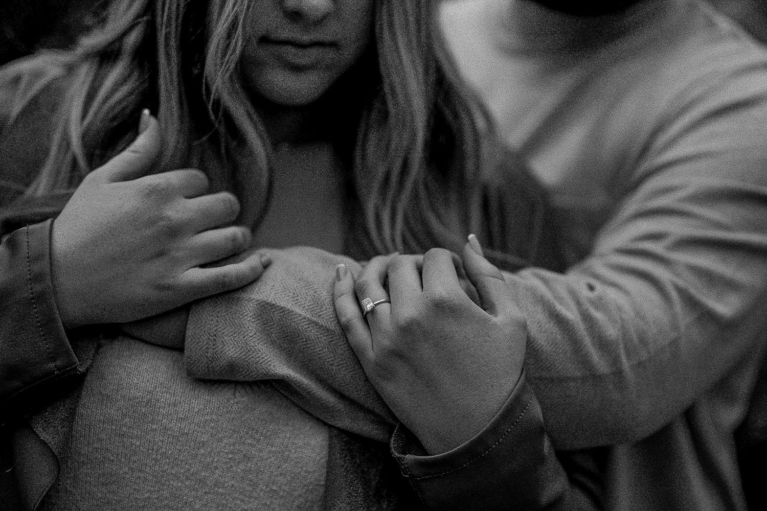 Black and white close-up of hands showing engagement ring.