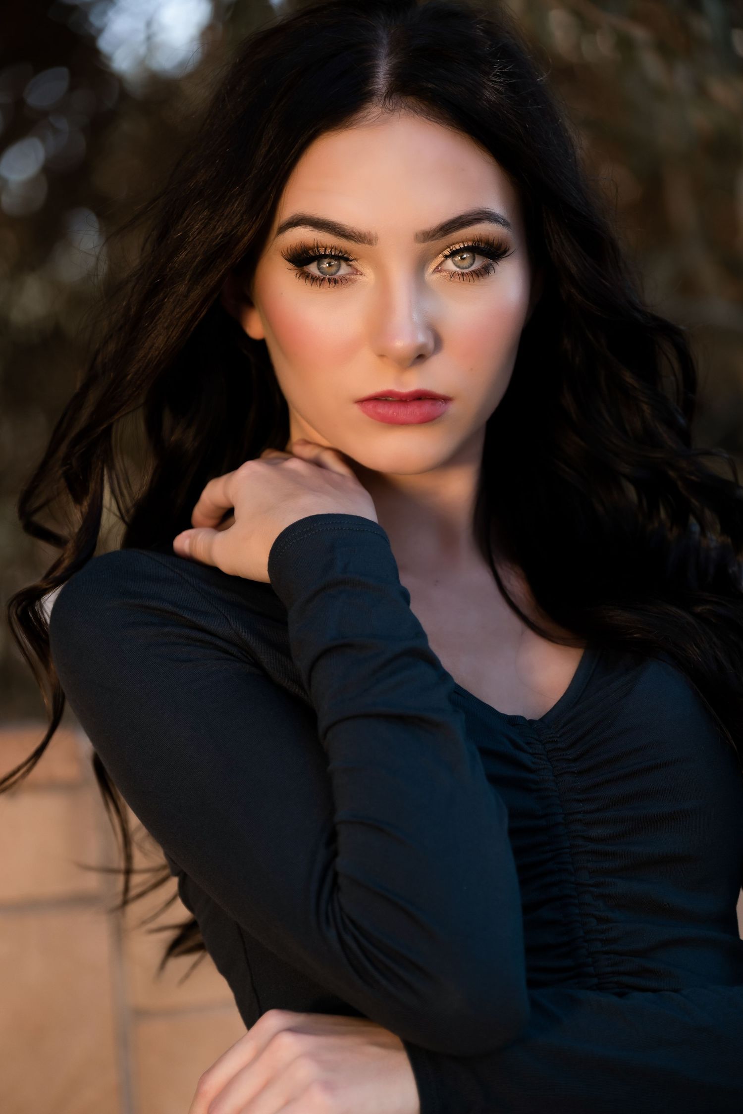 A series of moody outdoor portrait photos featuring dark hair and black clothing against a warm sunset background.