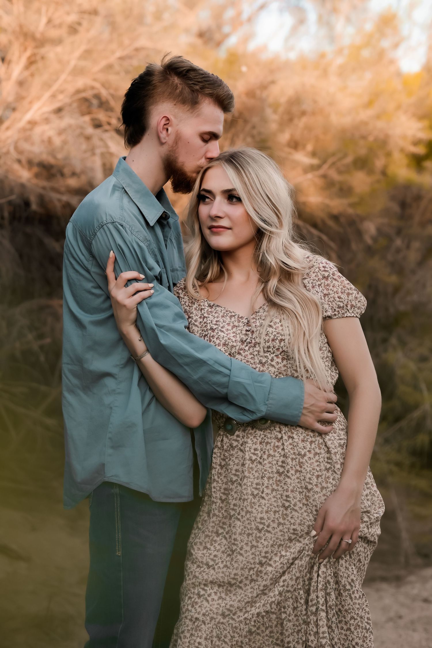 Couple embracing outdoors in autumn setting during engagement photo session.