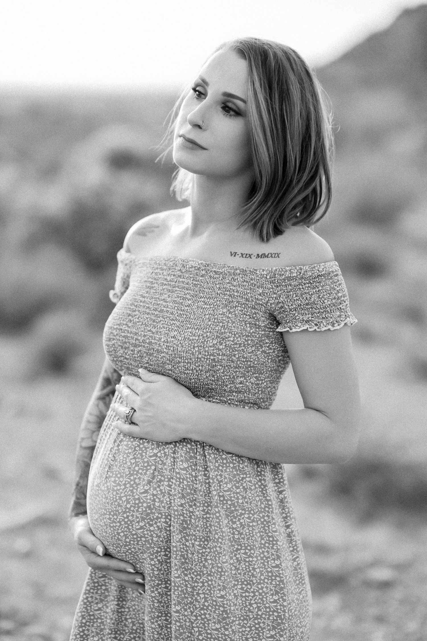 Black and white maternity portrait in desert setting with off-shoulder dress.