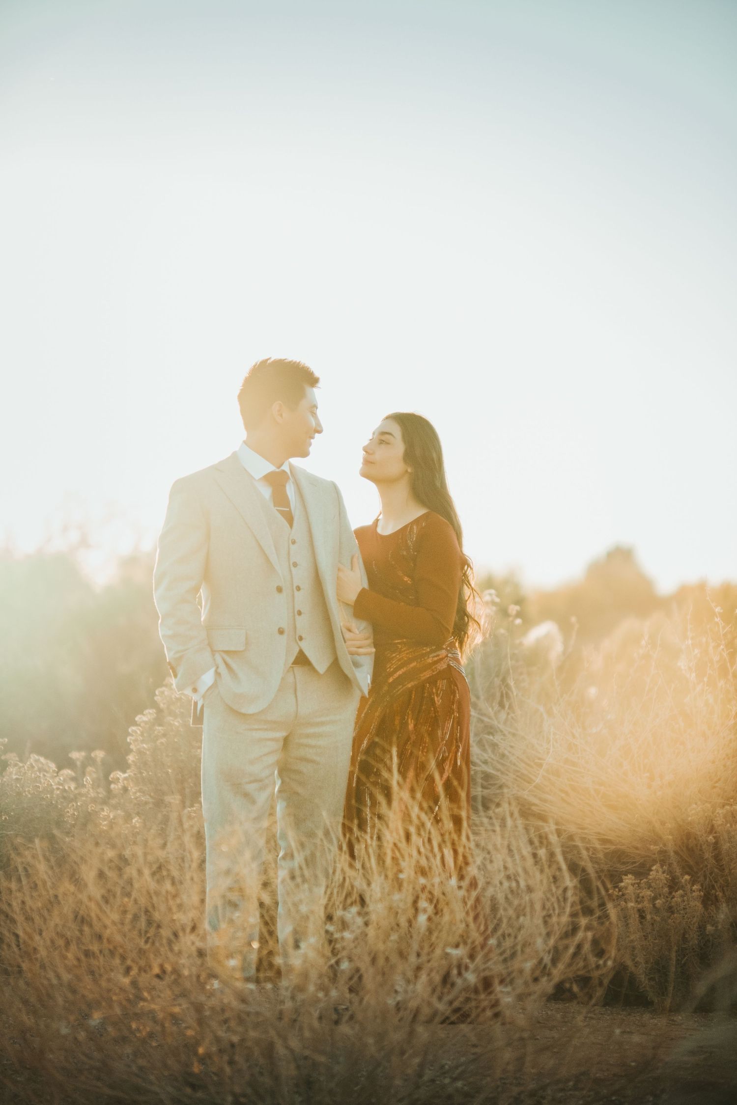 Couple standing in golden field during sunset engagement photoshoot.