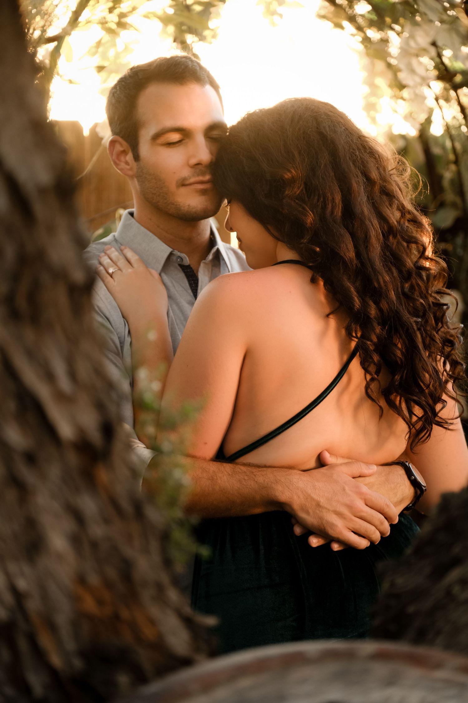 A tender embrace between a couple during golden hour in a natural outdoor setting.