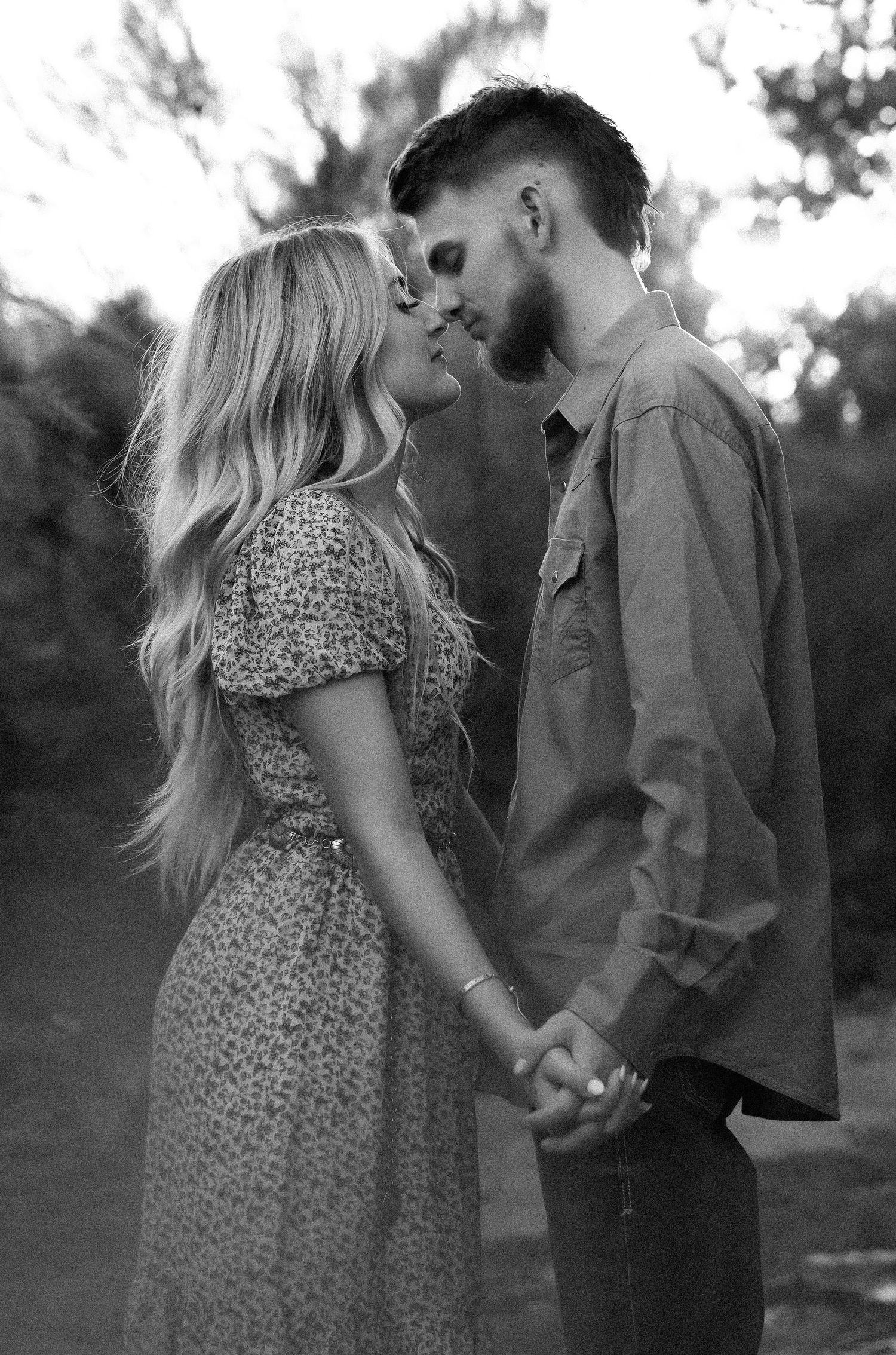 A romantic black and white portrait of a couple holding hands and sharing an intimate moment.