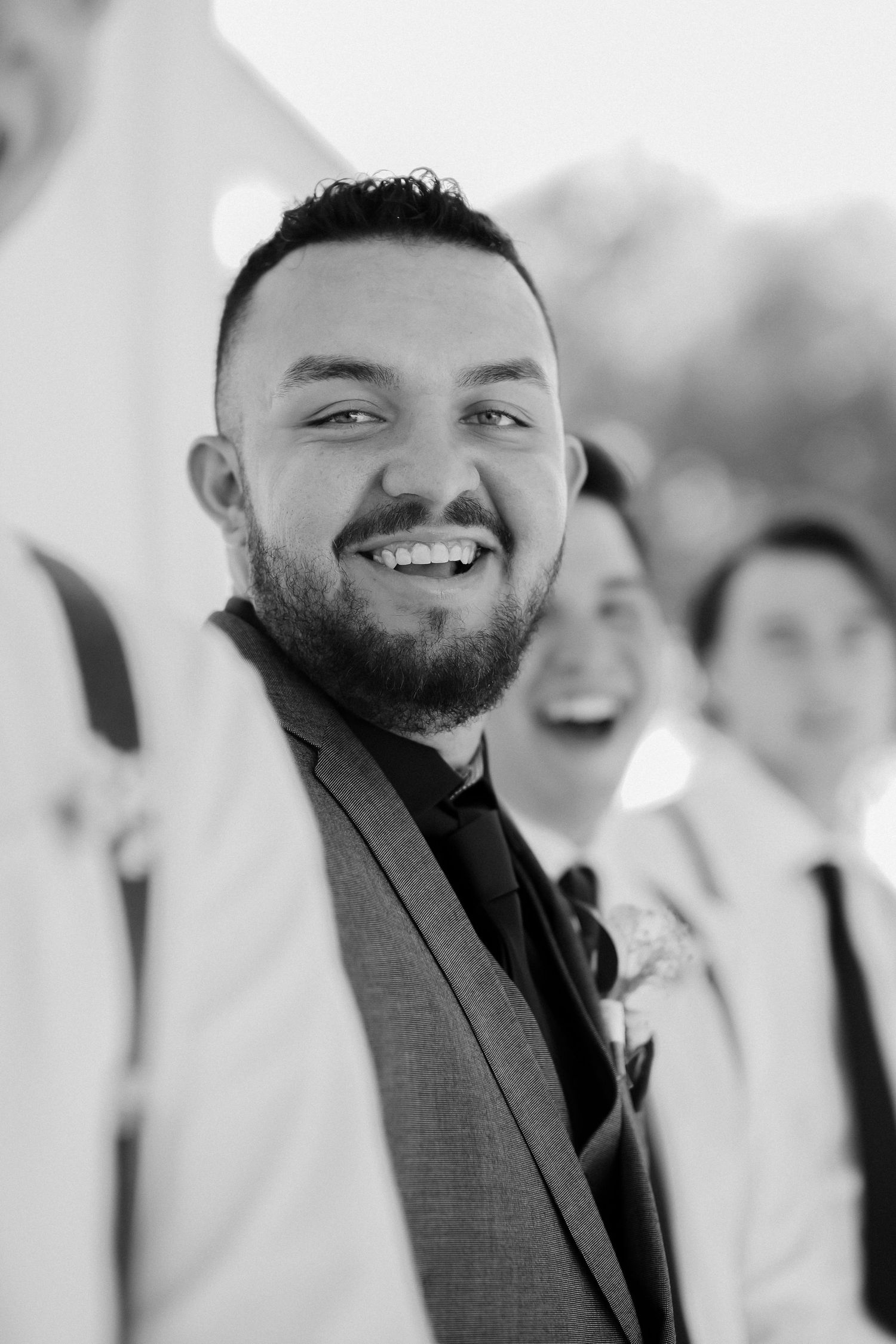 Black and white portrait of wedding party member smiling at camera.