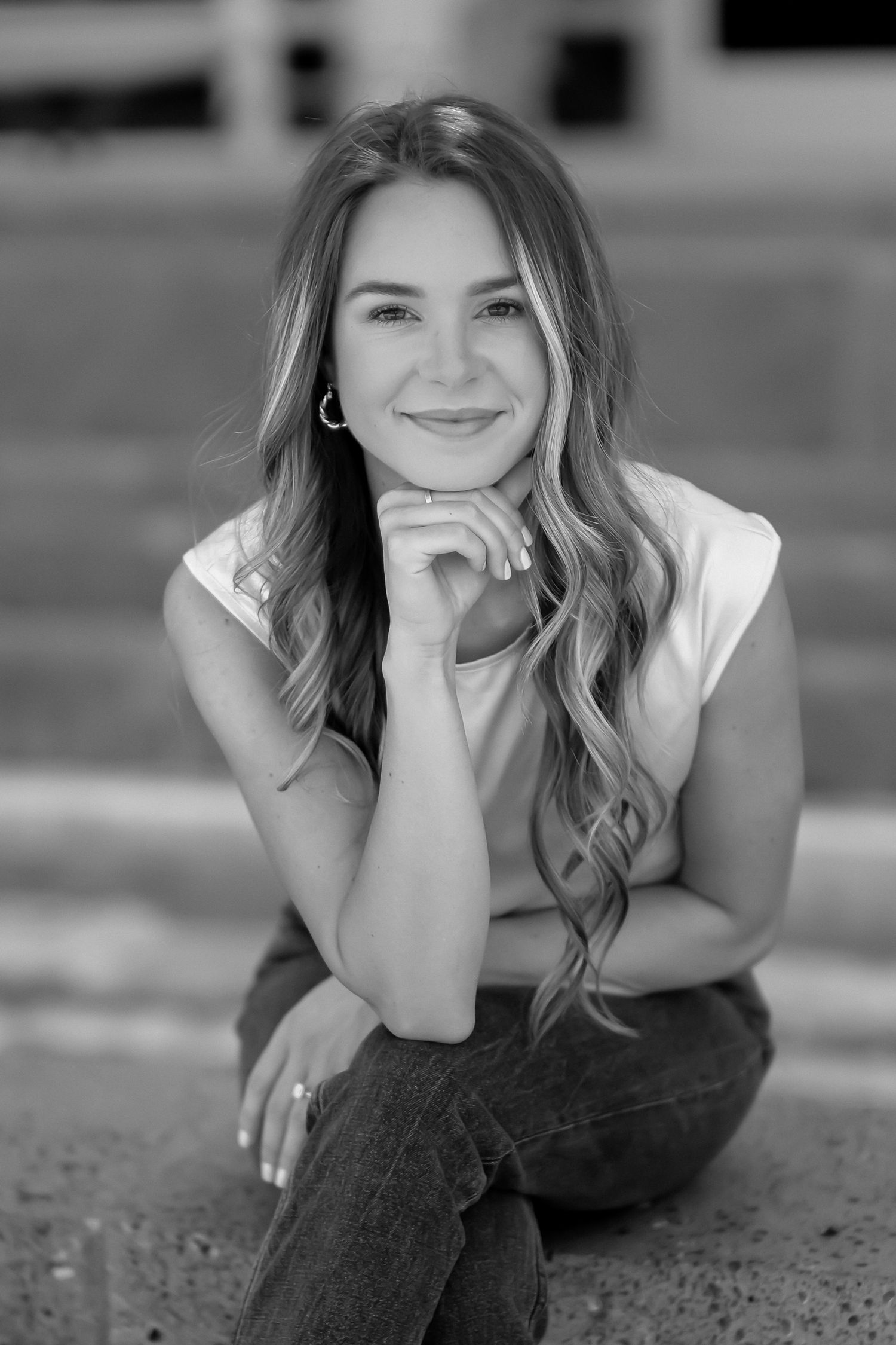 Black and white portrait with relaxed pose and wavy hair.