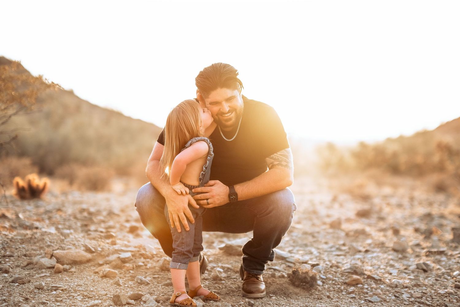 Parent and child sharing intimate moment in desert setting during golden hour.
