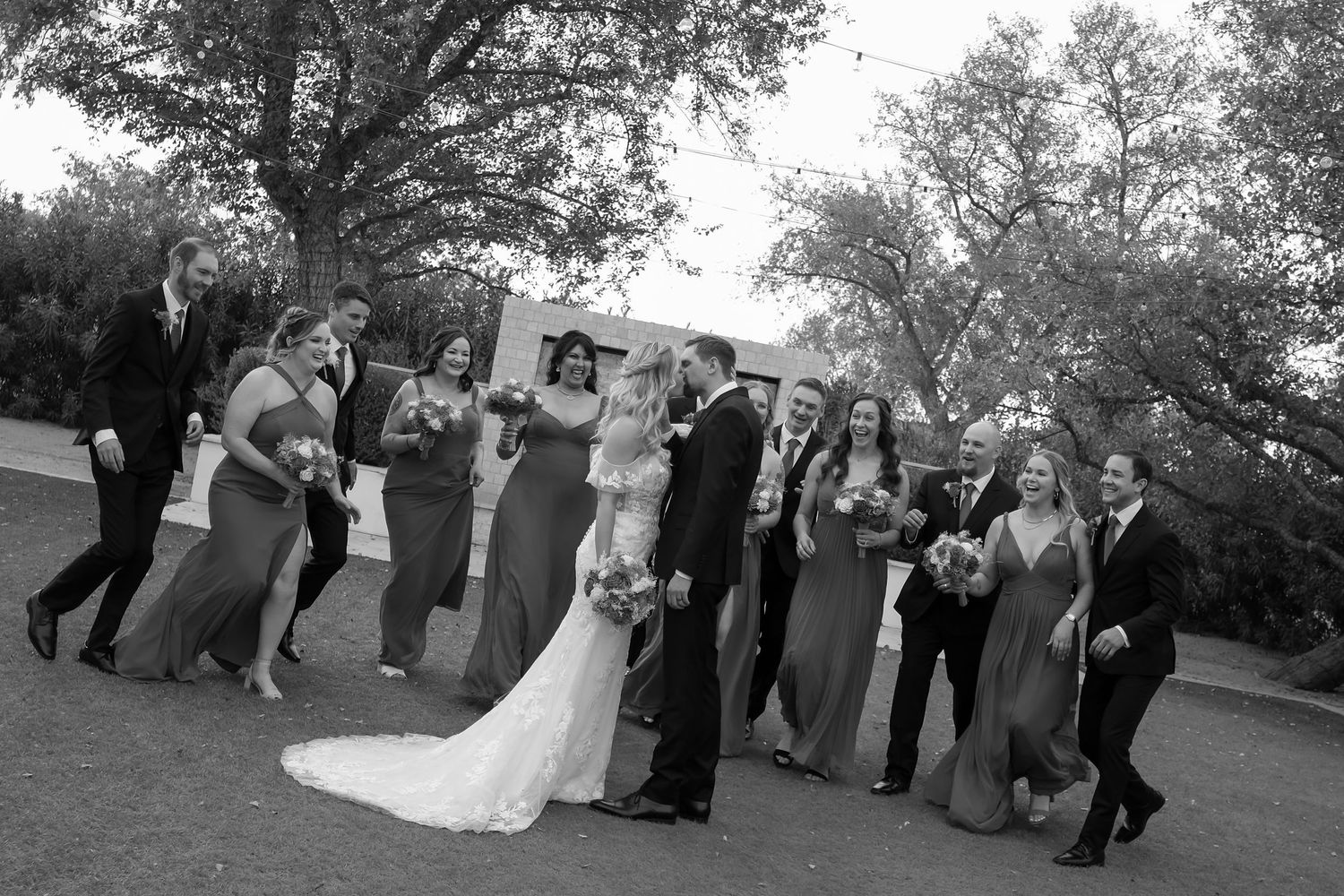 Black and white photo of a wedding party celebrating outdoors.