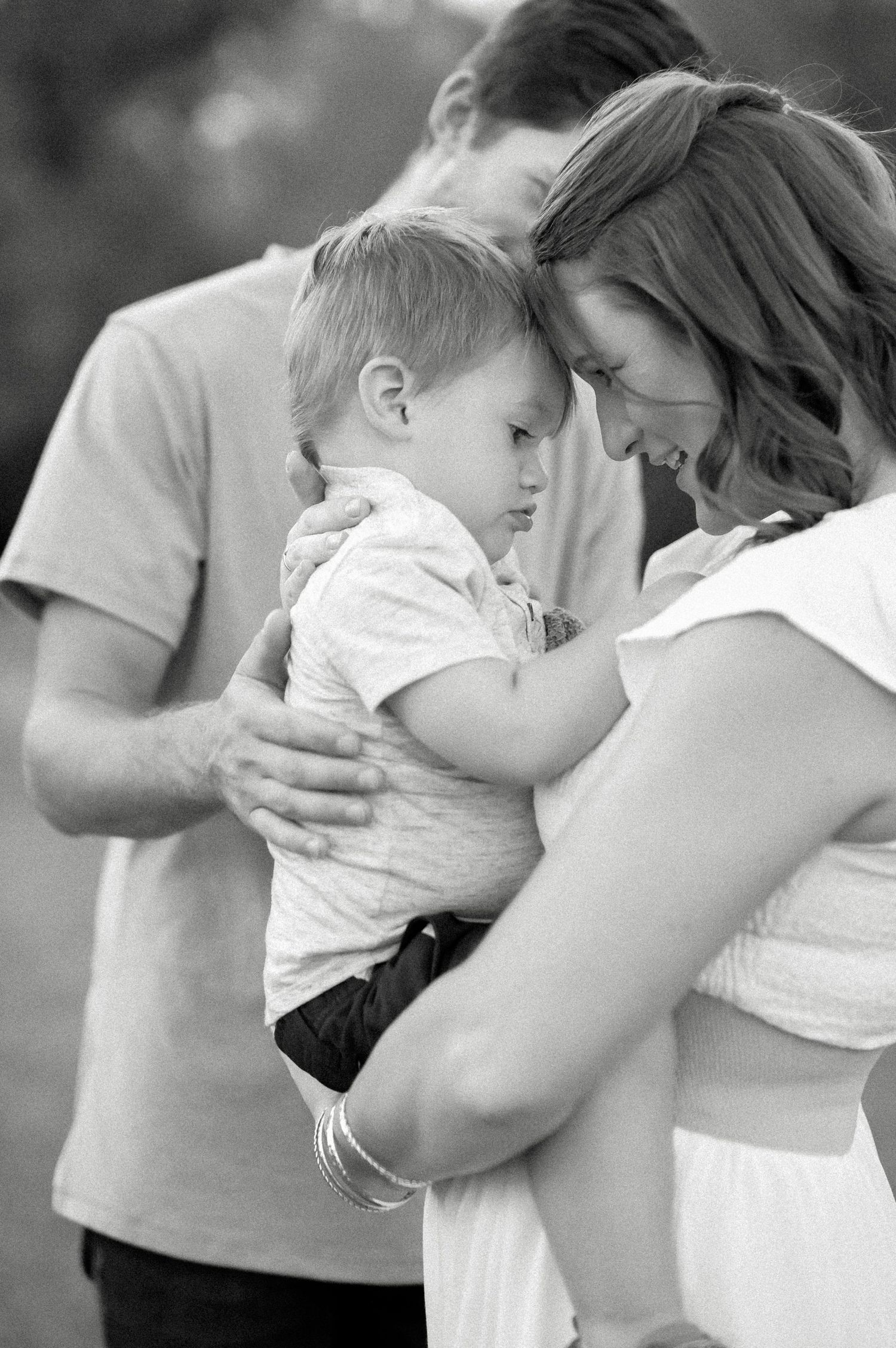 Intimate black and white family portrait showing tender moment with young child.