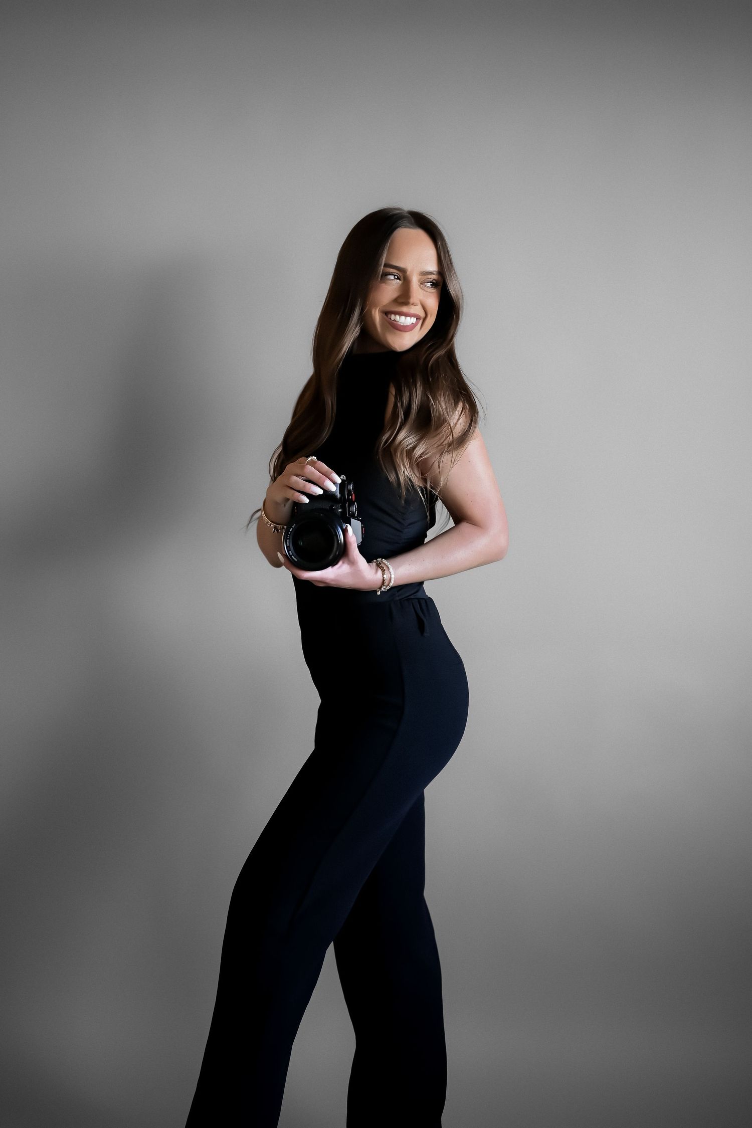 A series of black and white maternity photos showing a pregnant woman in a dark dress posing against a light background.