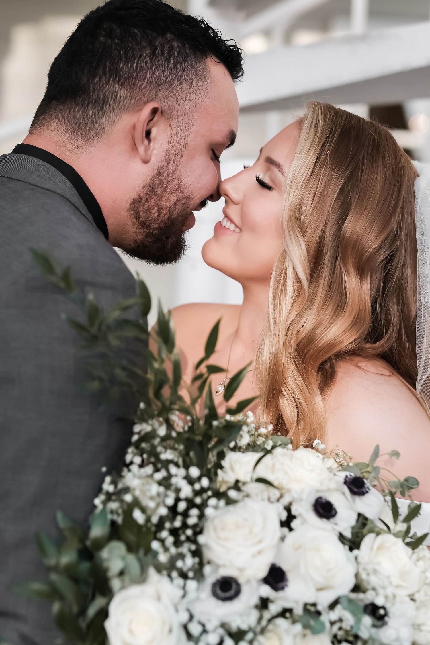 A romantic wedding couple shares an intimate moment with a bouquet of white anemone and eucalyptus flowers.