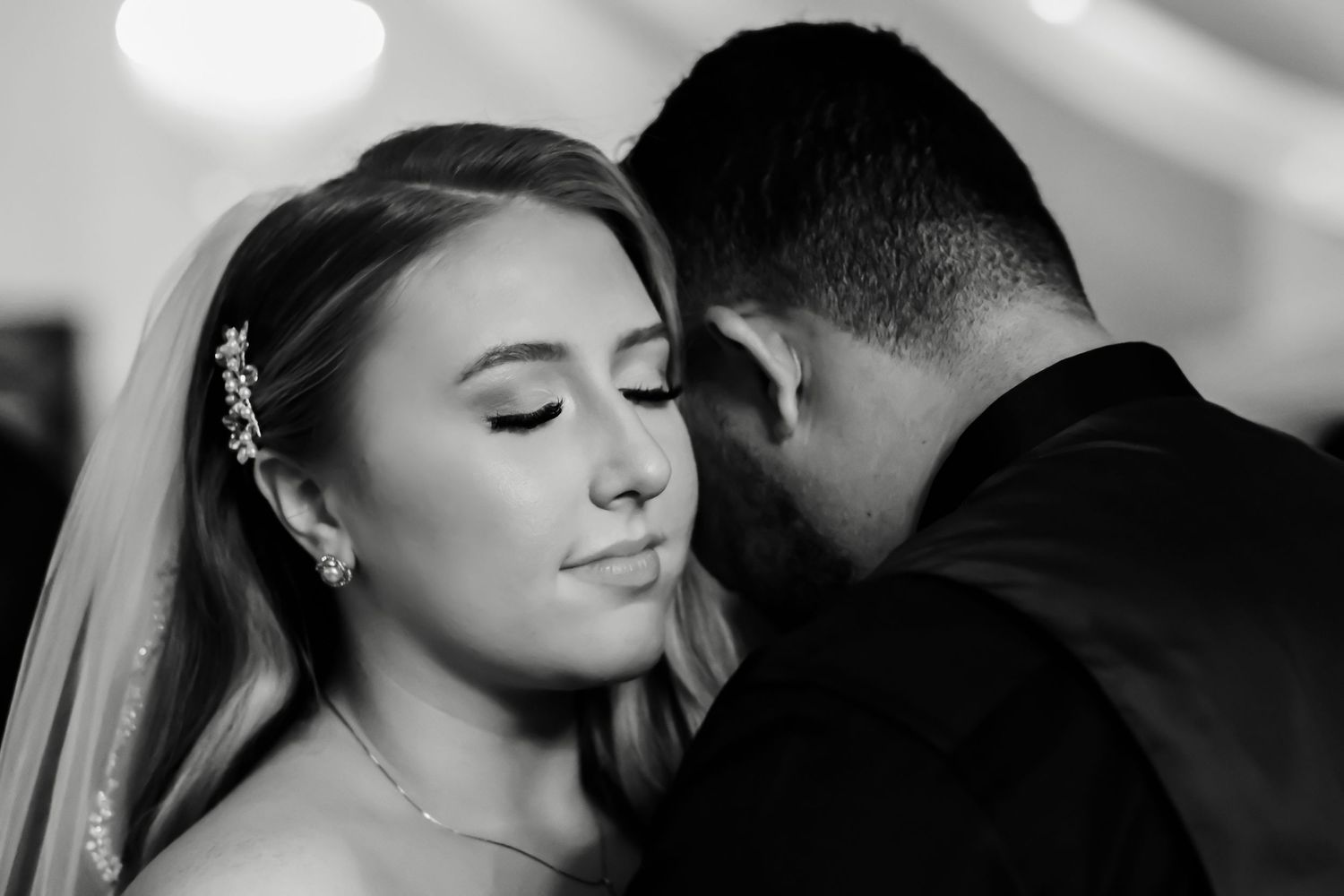 Black and white intimate wedding portrait showing romantic moment between bride and groom with soft veil details.