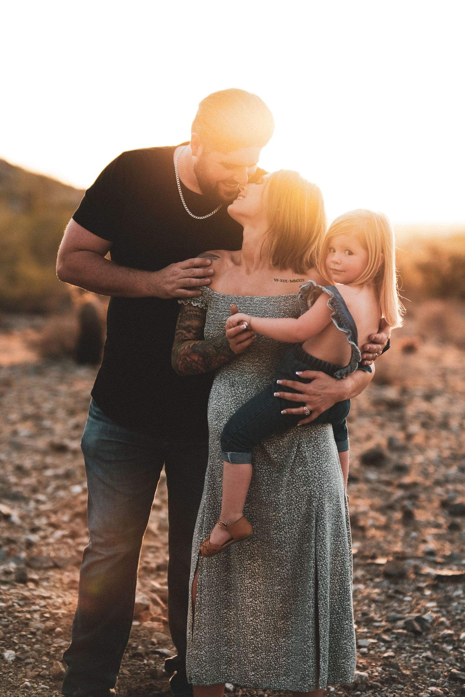 A tender family moment captured at sunset in a desert setting with warm golden light.