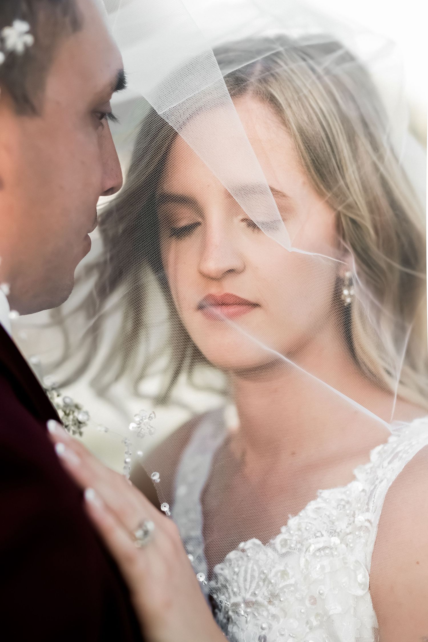 Close-up detail shots of a bride wearing a delicate lace wedding dress and veil in romantic natural lighting.