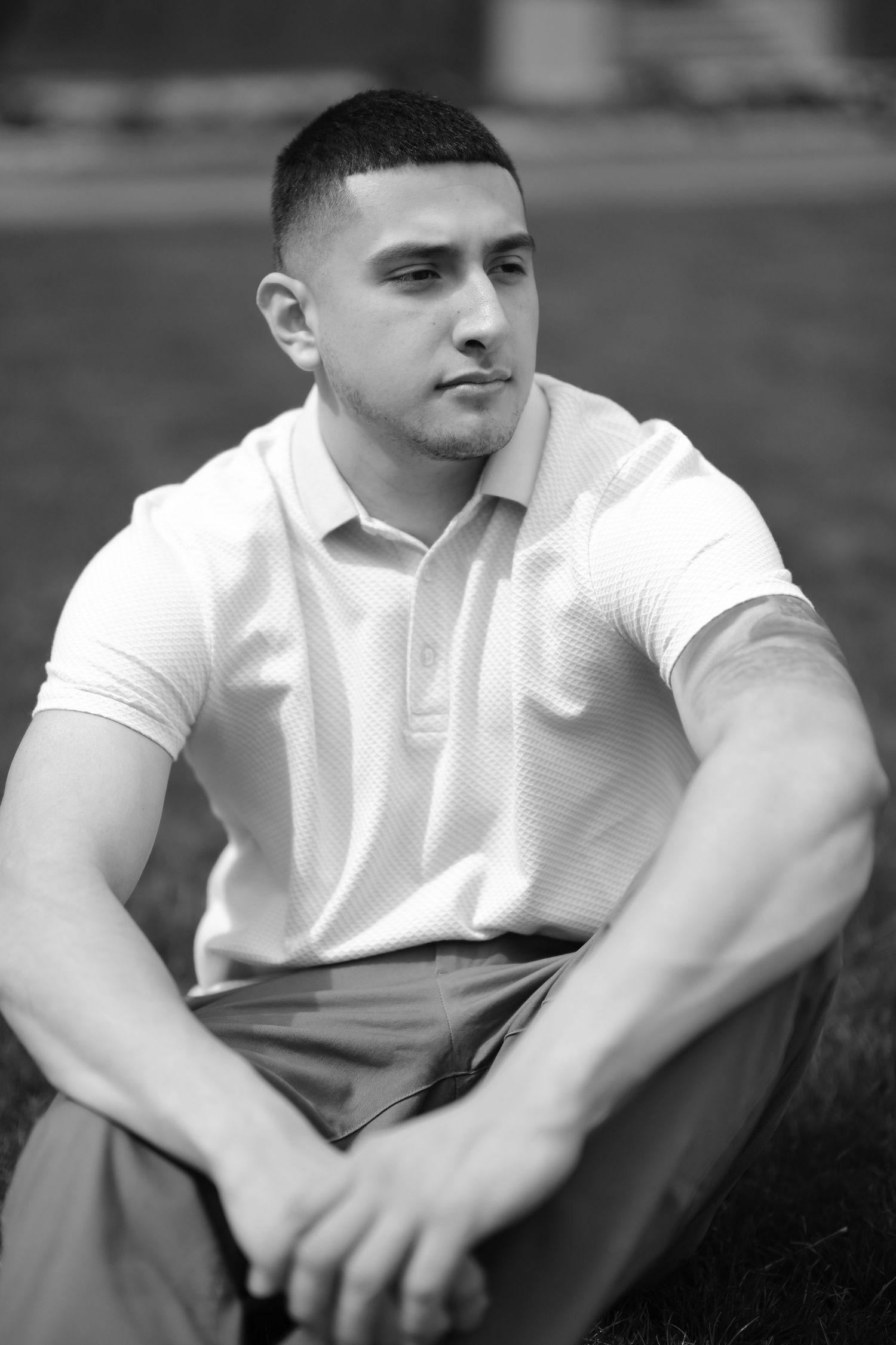 Professional portrait of person in white polo shirt against dark background.