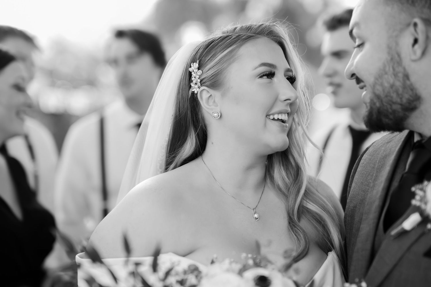 A joyful moment captured in black and white at a wedding reception as the bride shares a laugh with someone nearby.