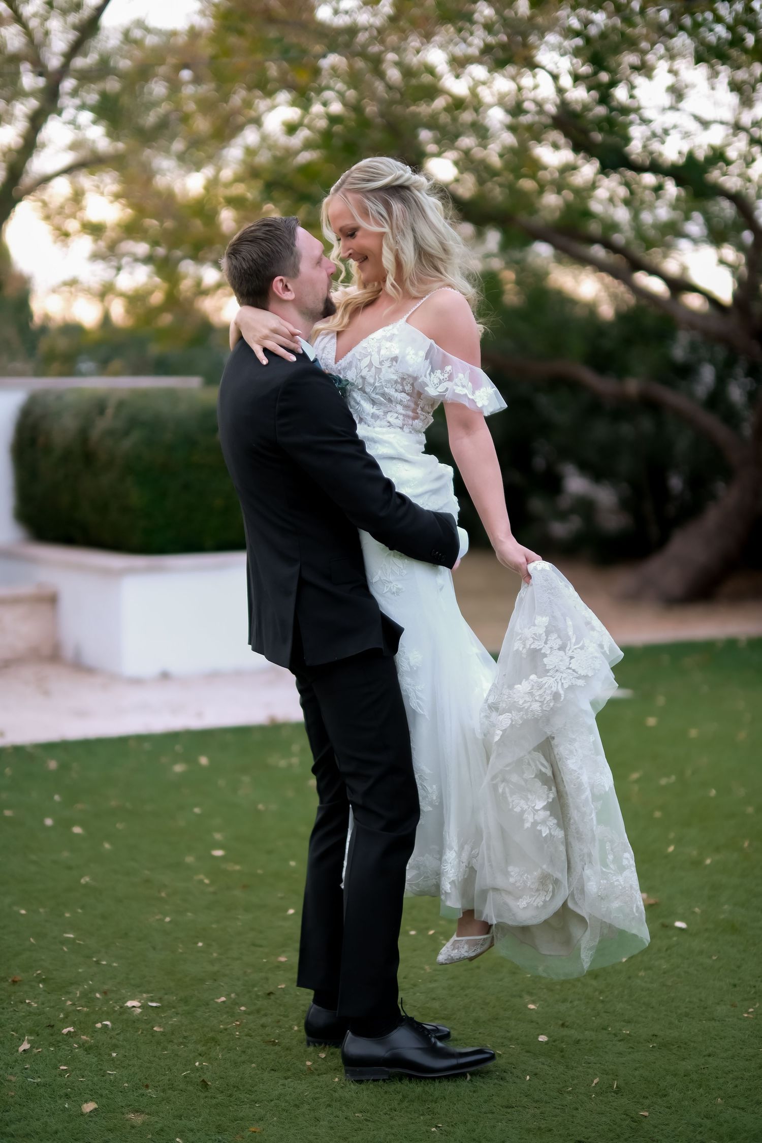 Romantic moment between newlyweds on manicured lawn during wedding photoshoot.