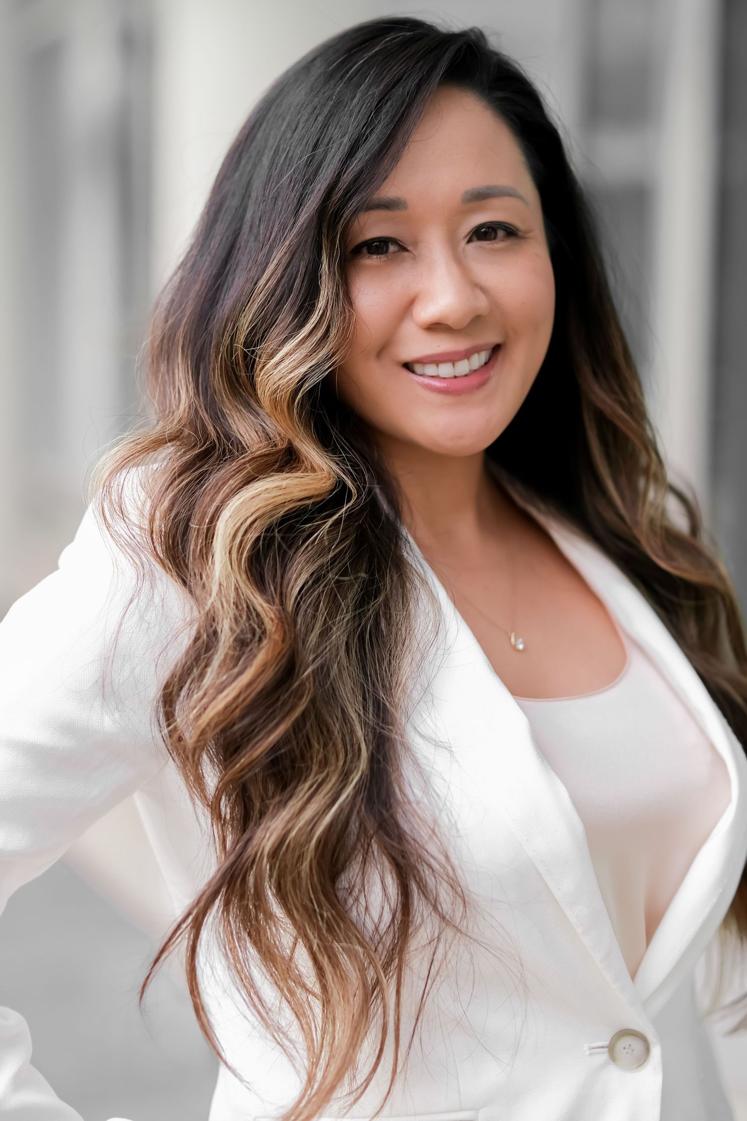 Professional headshot featuring white blazer and ombre hair styling.