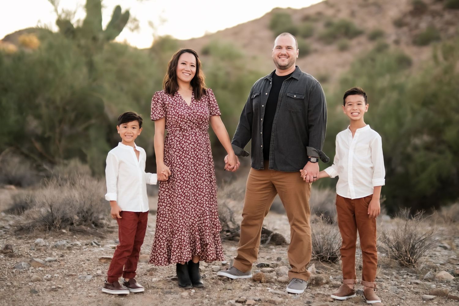 Desert family portrait with desert landscape and cacti in background at sunset.