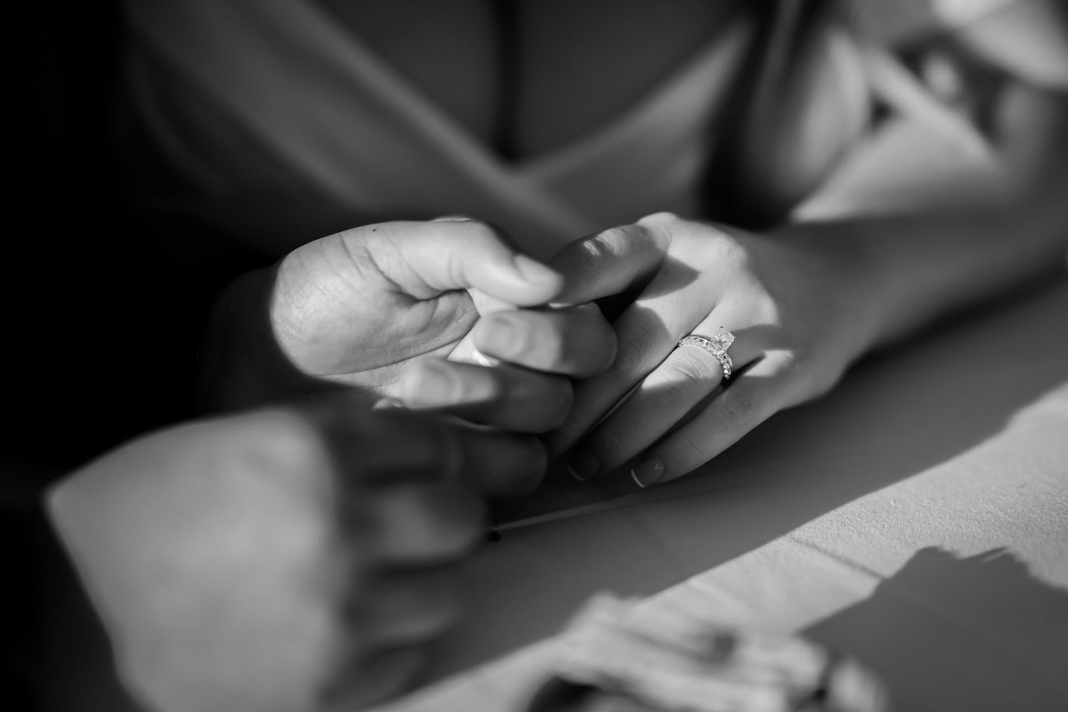 Hands holding and examining playing cards in black and white, creating a contemplative gaming moment.