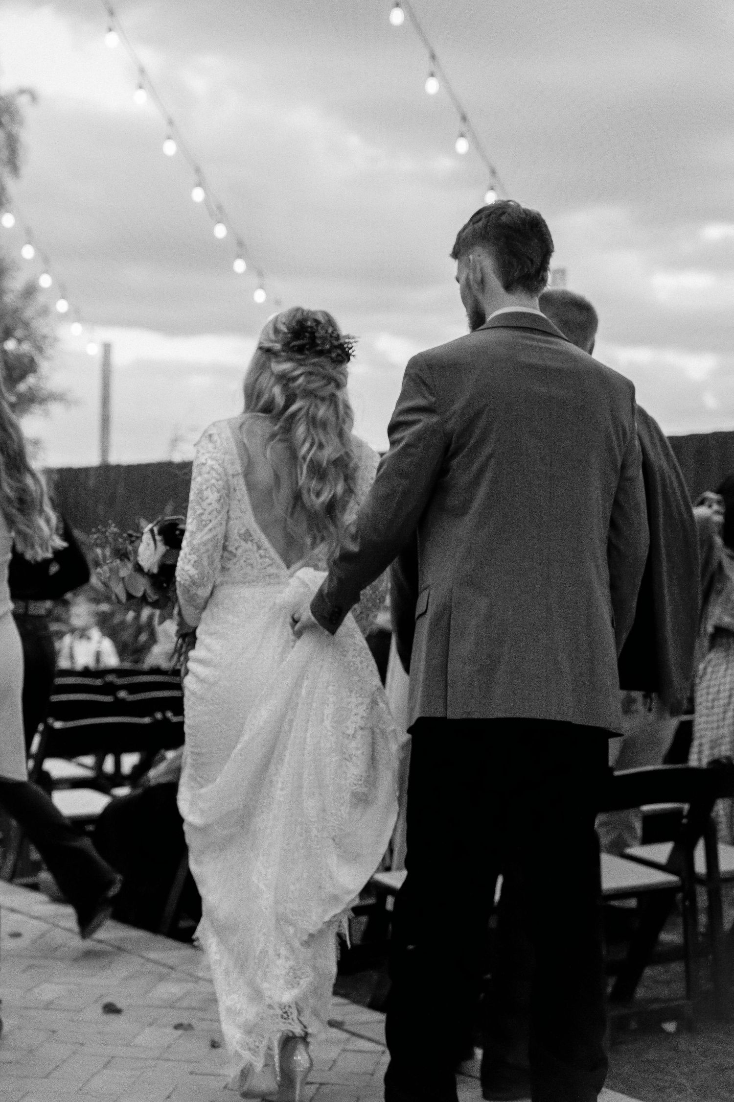 Black and white photo series showing a couple walking together at an outdoor wedding celebration.