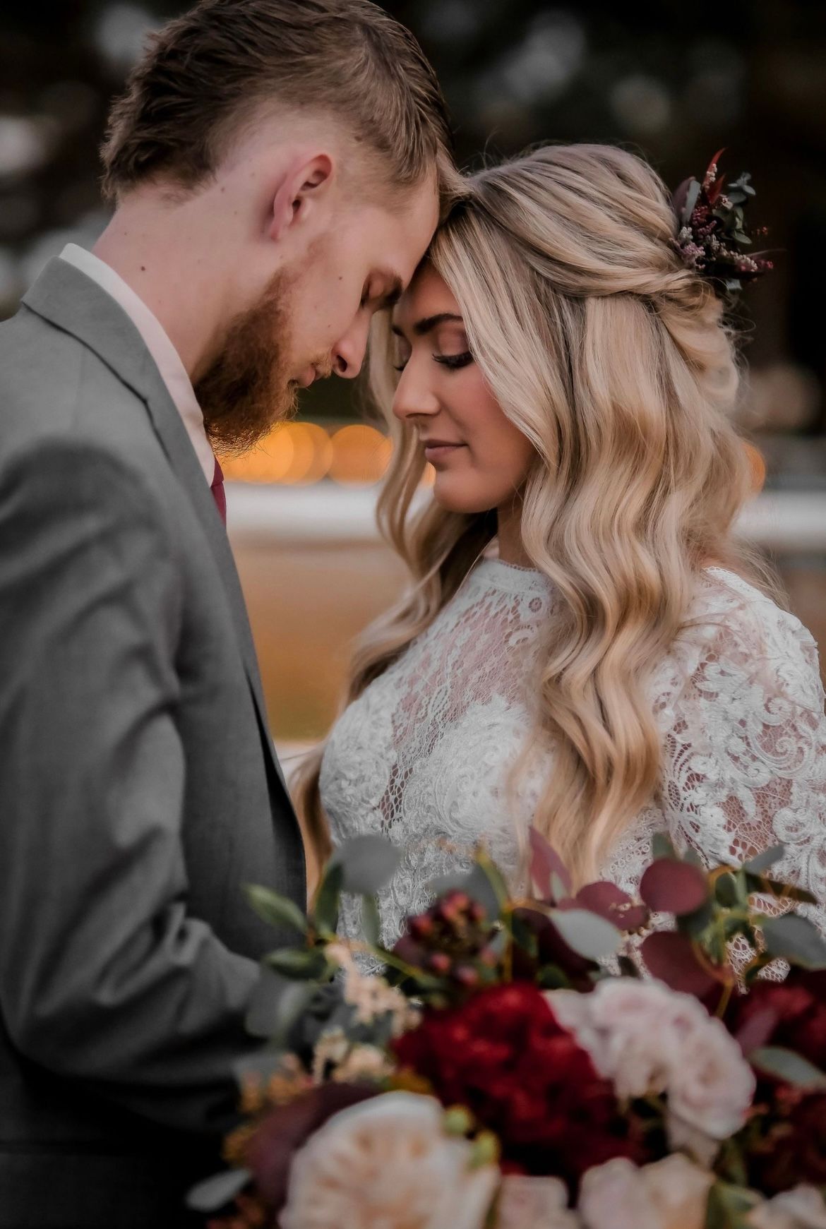 Romantic sunset portrait of newlyweds with burgundy and blush bouquet.