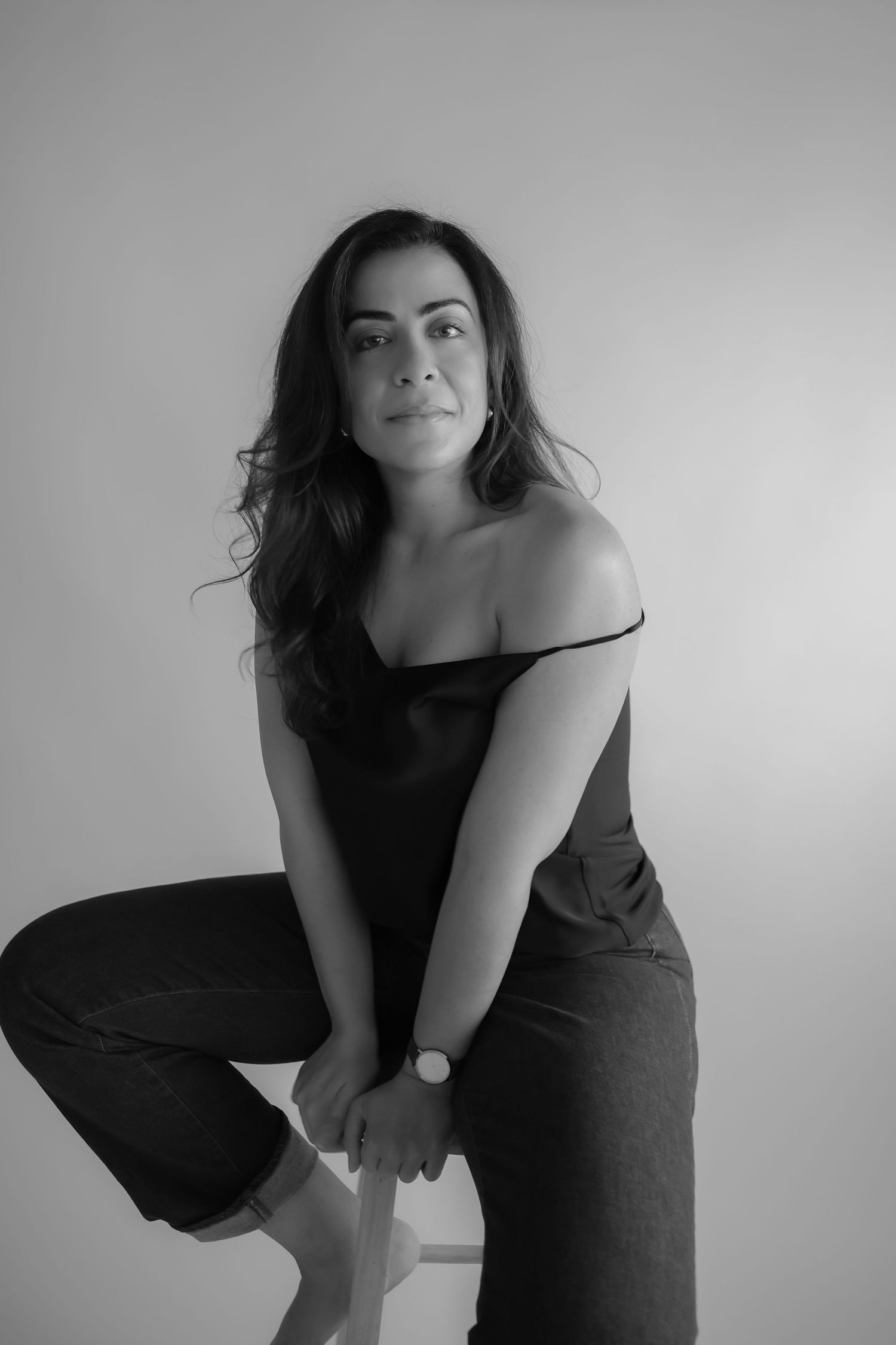 Black and white portrait of someone in casual attire posing against a plain wall in an artistic style.