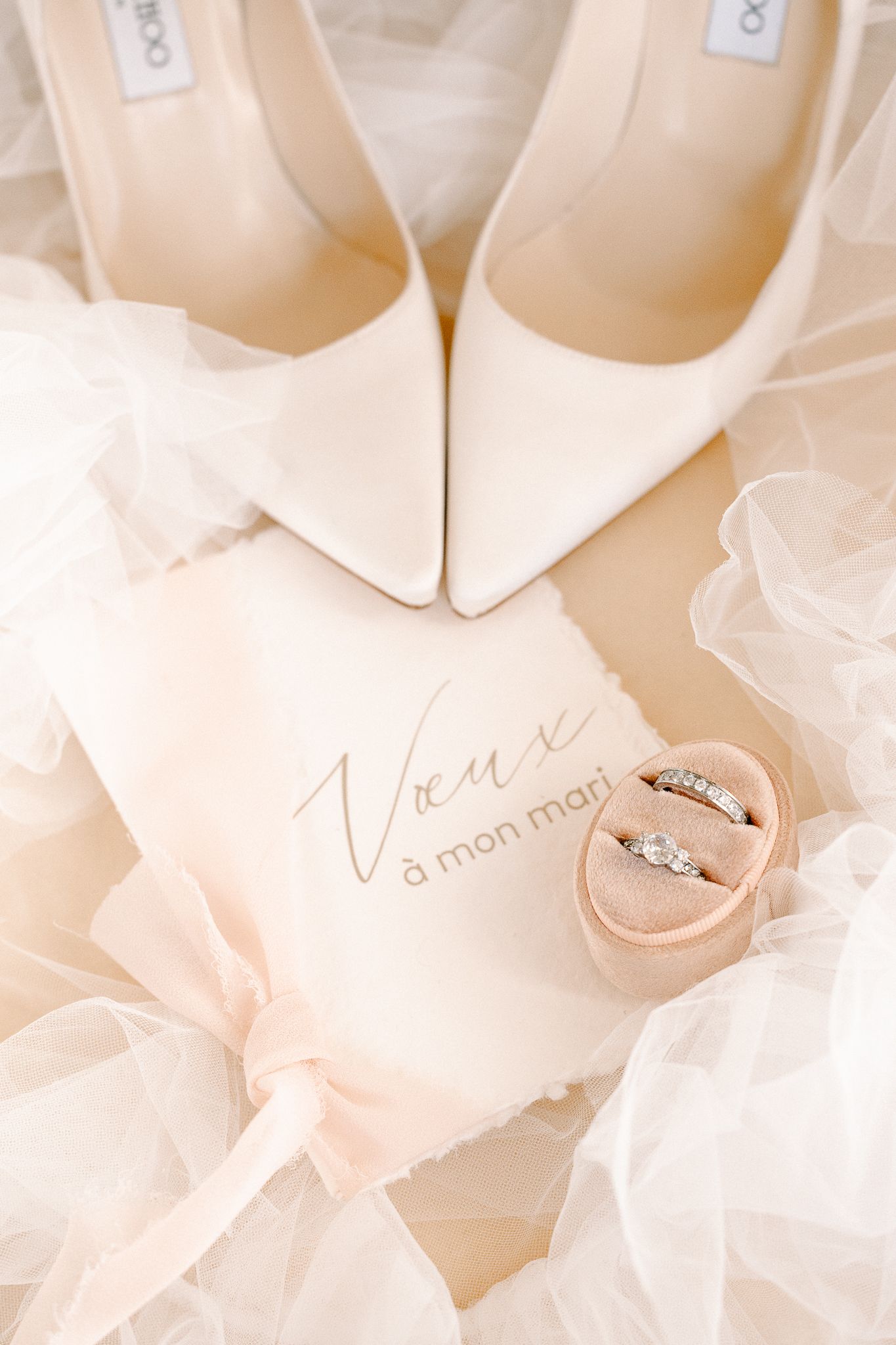 Wedding details with ivory heels, ring box and rings on light background.