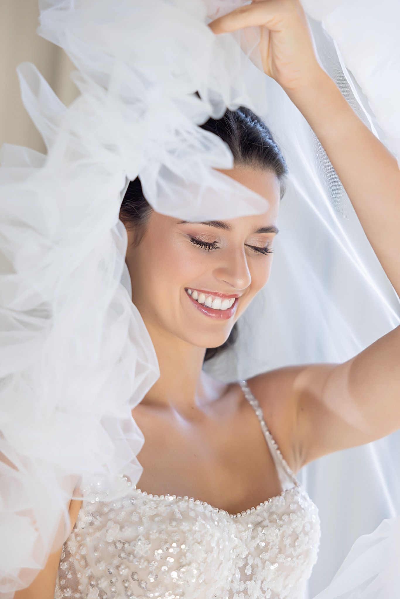 Ethereal bridal portrait with flowing veil and beaded wedding dress.