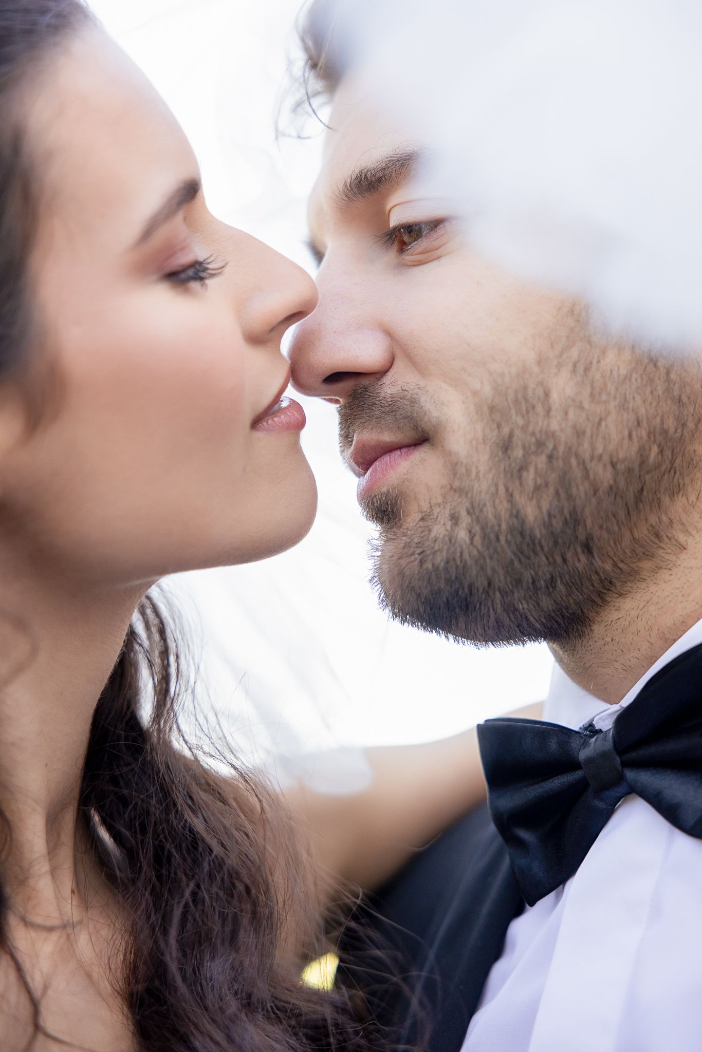 Romantic close-up of couple about to kiss through ethereal veil.