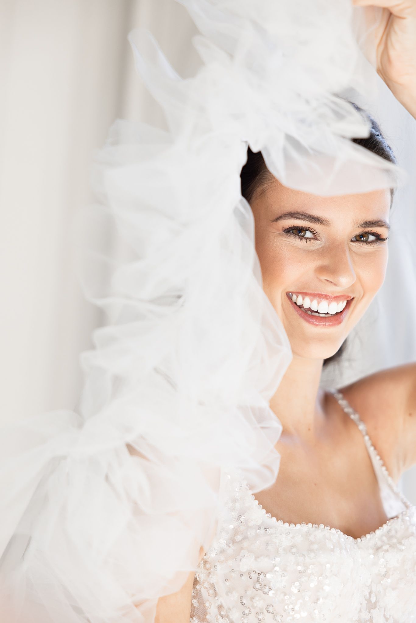 Close-up portrait of bride with radiant smile wearing tulle veil.