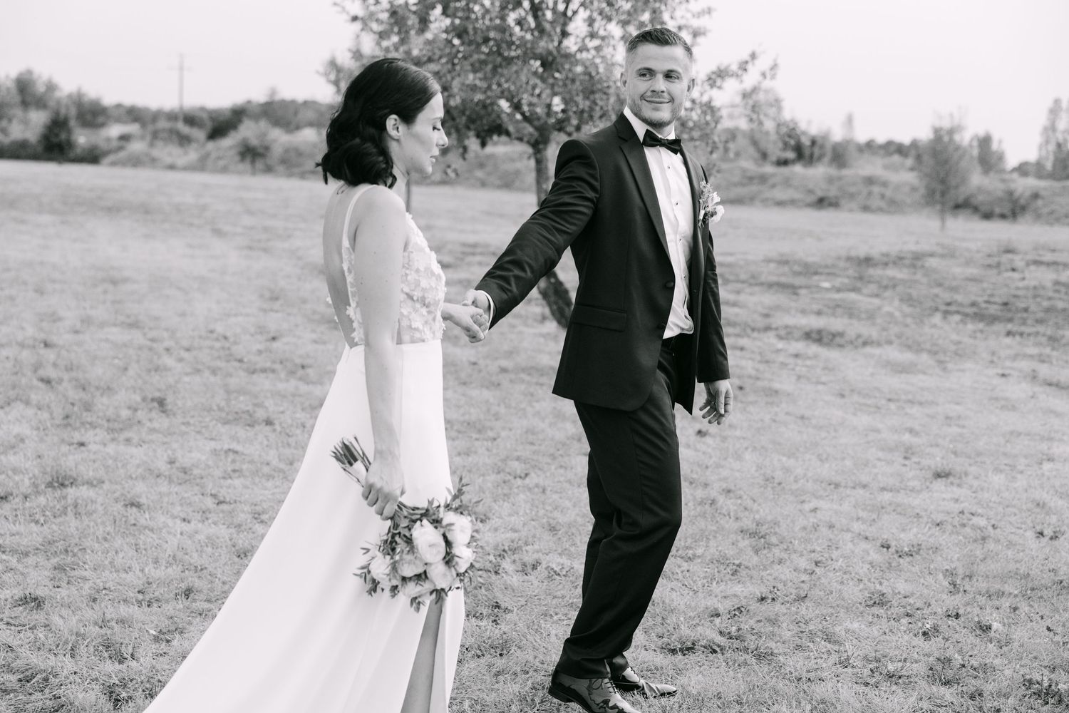 A black and white series of romantic wedding portraits showing a couple walking and embracing in a grassy meadow.