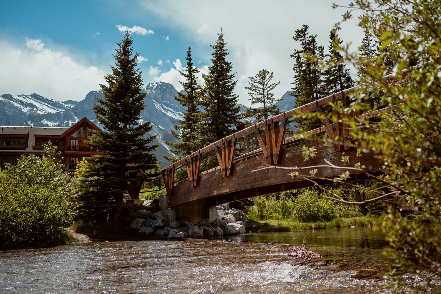 Panoramic mountain landscape with snow-capped peaks and wooden structures.