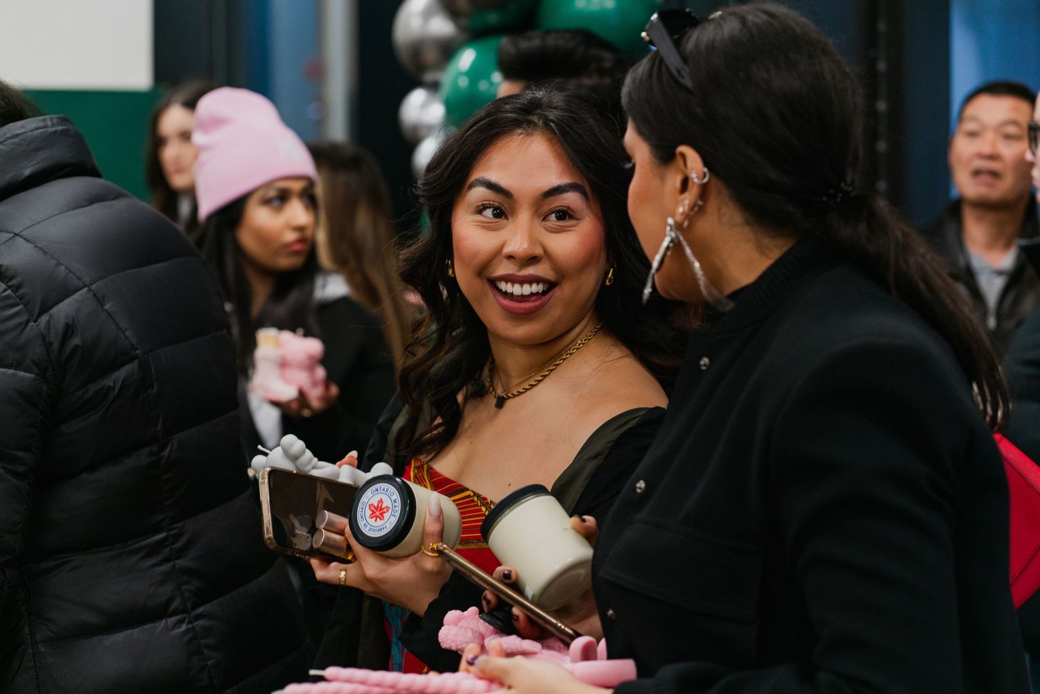 People gathered at a social event with winter coats and beverages.