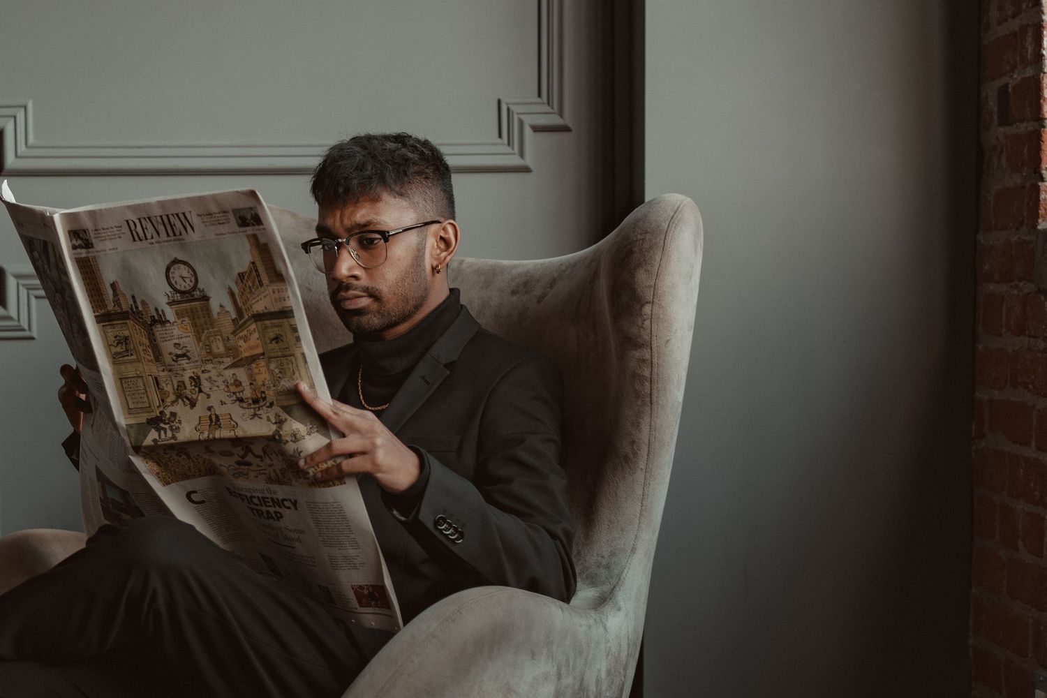 Person reading a newspaper in a dimly lit room with dramatic lighting.