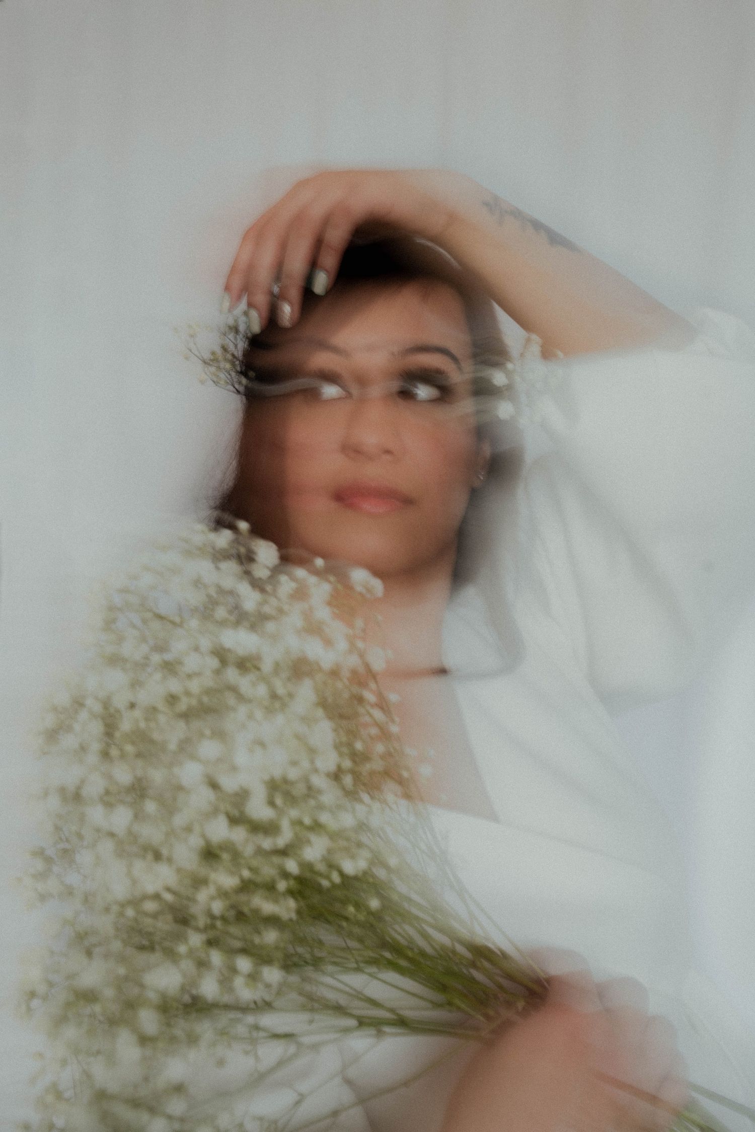 Dreamy portrait with baby's breath flowers creating soft motion blur effect.