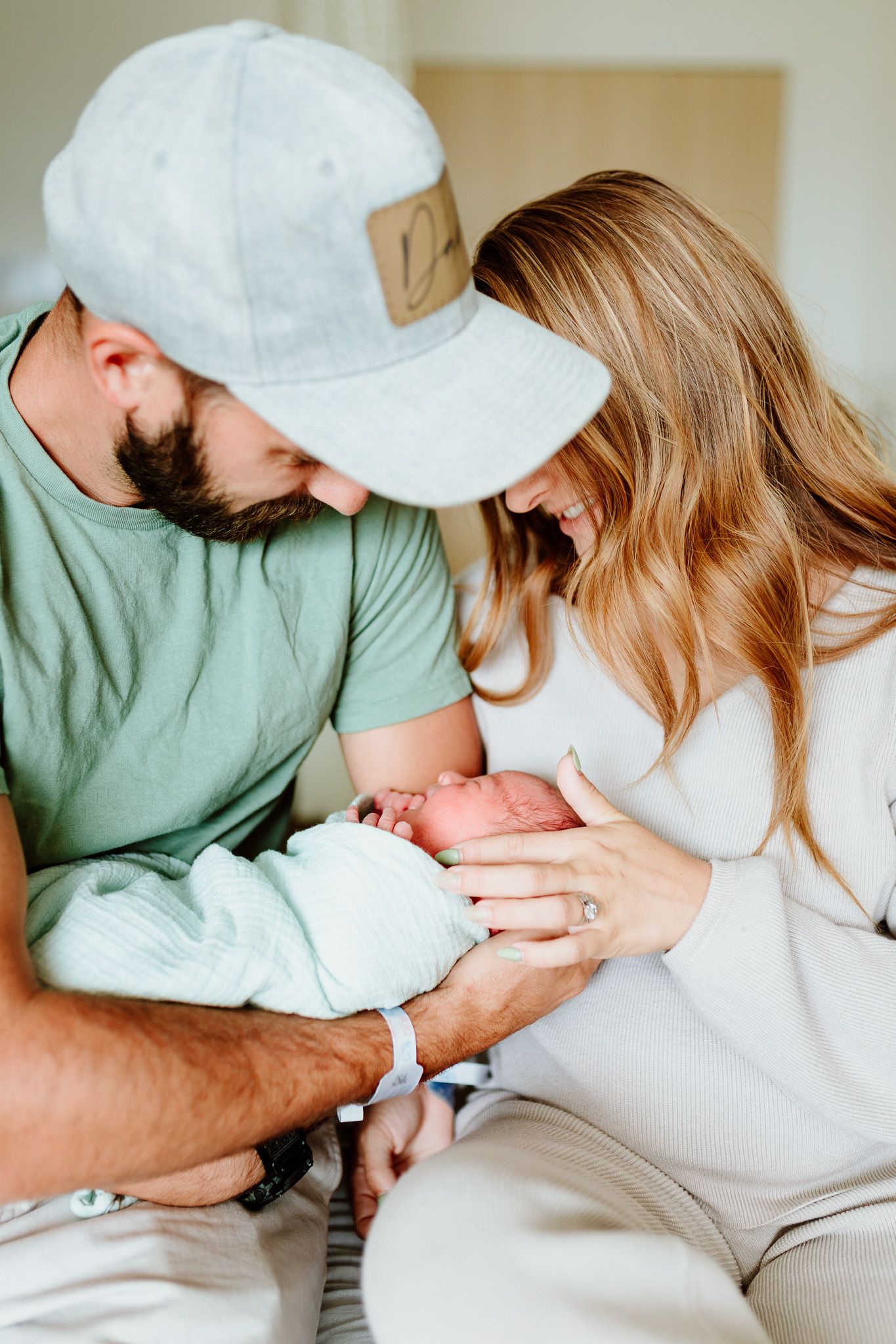 Parents in casual attire lovingly hold and gaze at their newborn baby. Fresh 48. Charleston, South Carolina. Salt and Oak Photography.