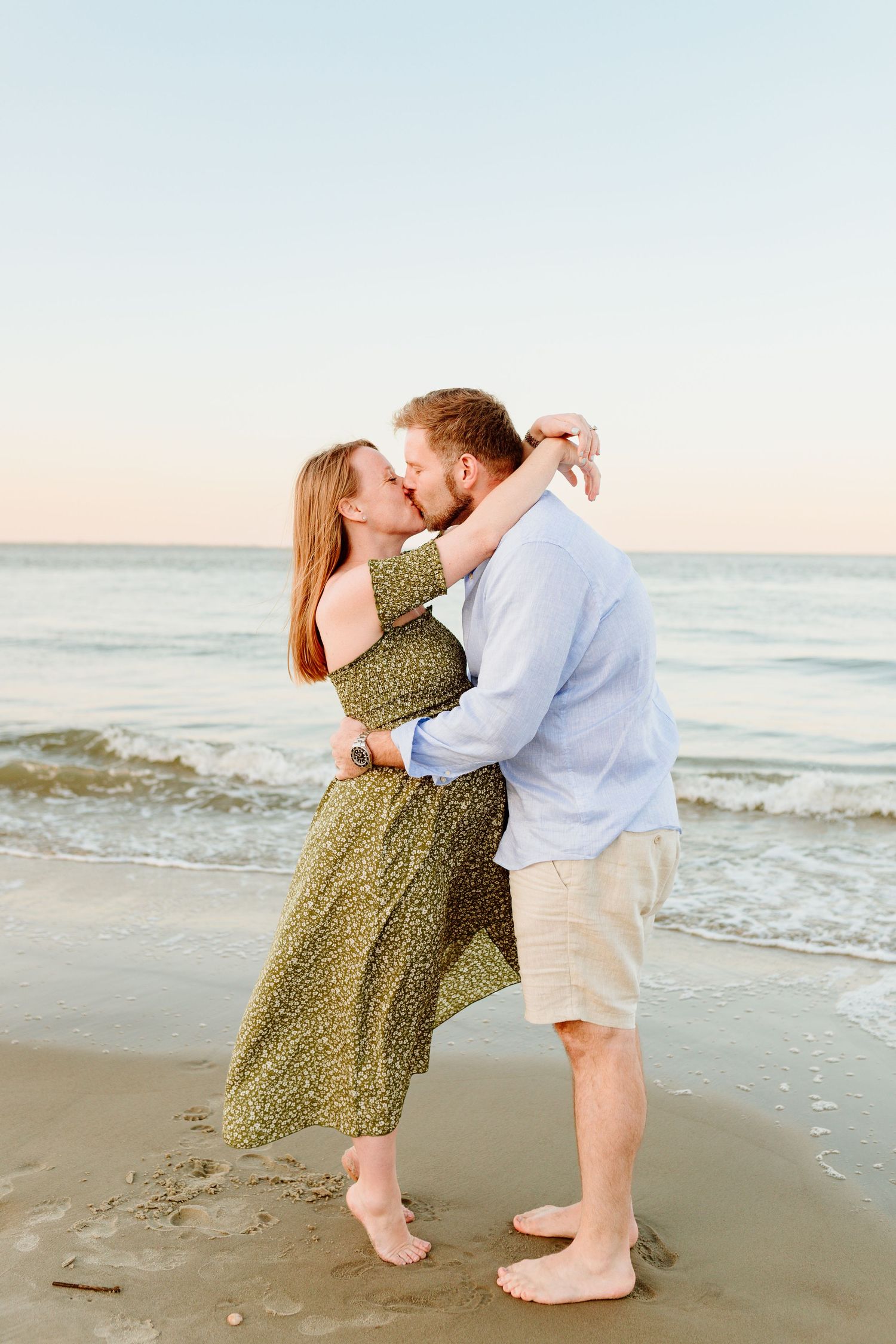 A romantic couple kisses on the beach at sunset wearing casual summer attire. Charleston, South Carolina. Salt and Oak Photography.