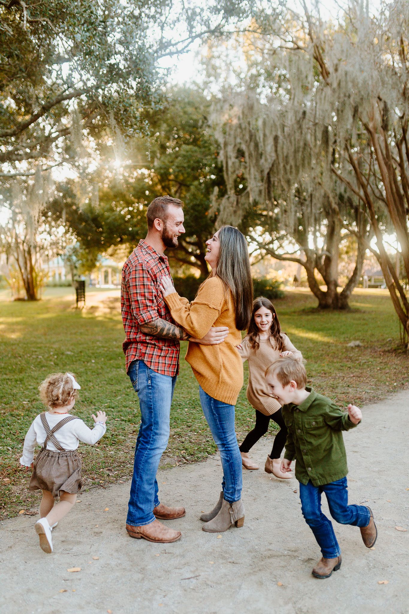 Family enjoys playful moment on path with children running and jumping. Charleston, South Carolina. Salt and Oak Photography.