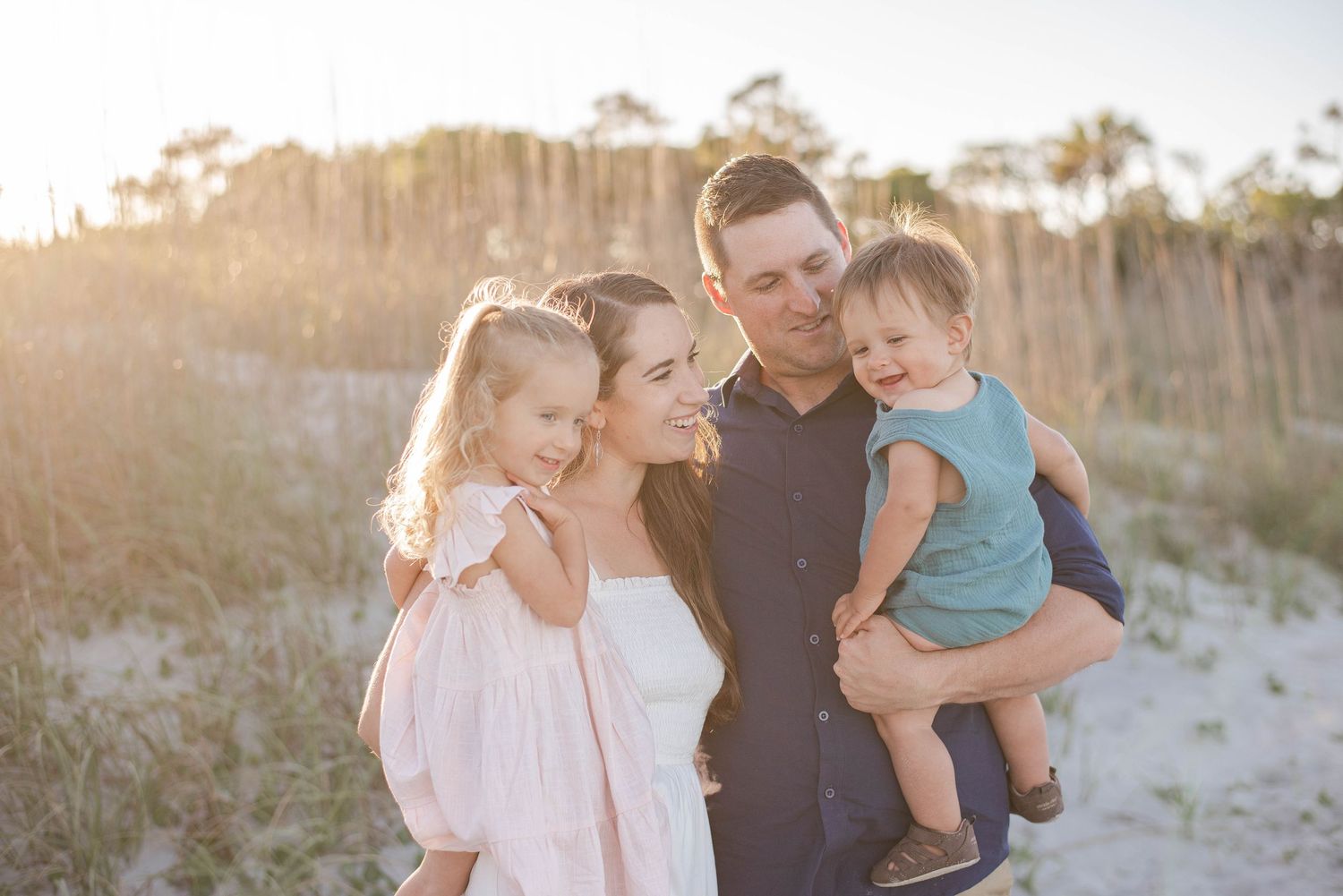 Intimate family portrait on beach dunes backlit by golden sunset light. Charleston, South Carolina. Salt and Oak Photography.