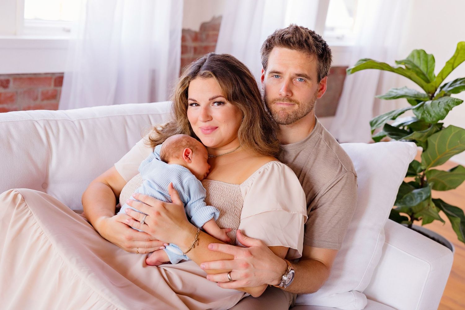 Intimate newborn lifestyle photo session showing tender moments on a white bed.