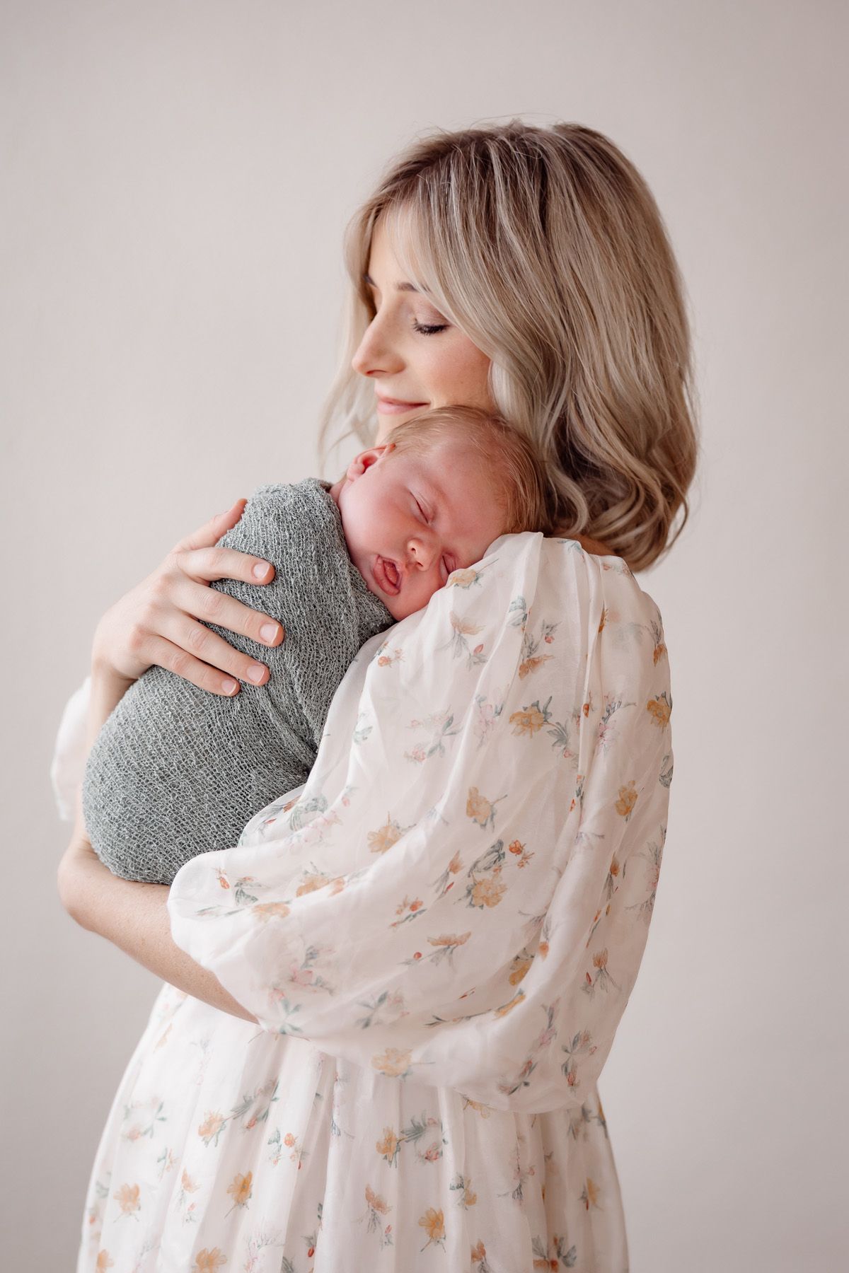 Dreamy newborn photography featuring soft floral dress and natural window light.
