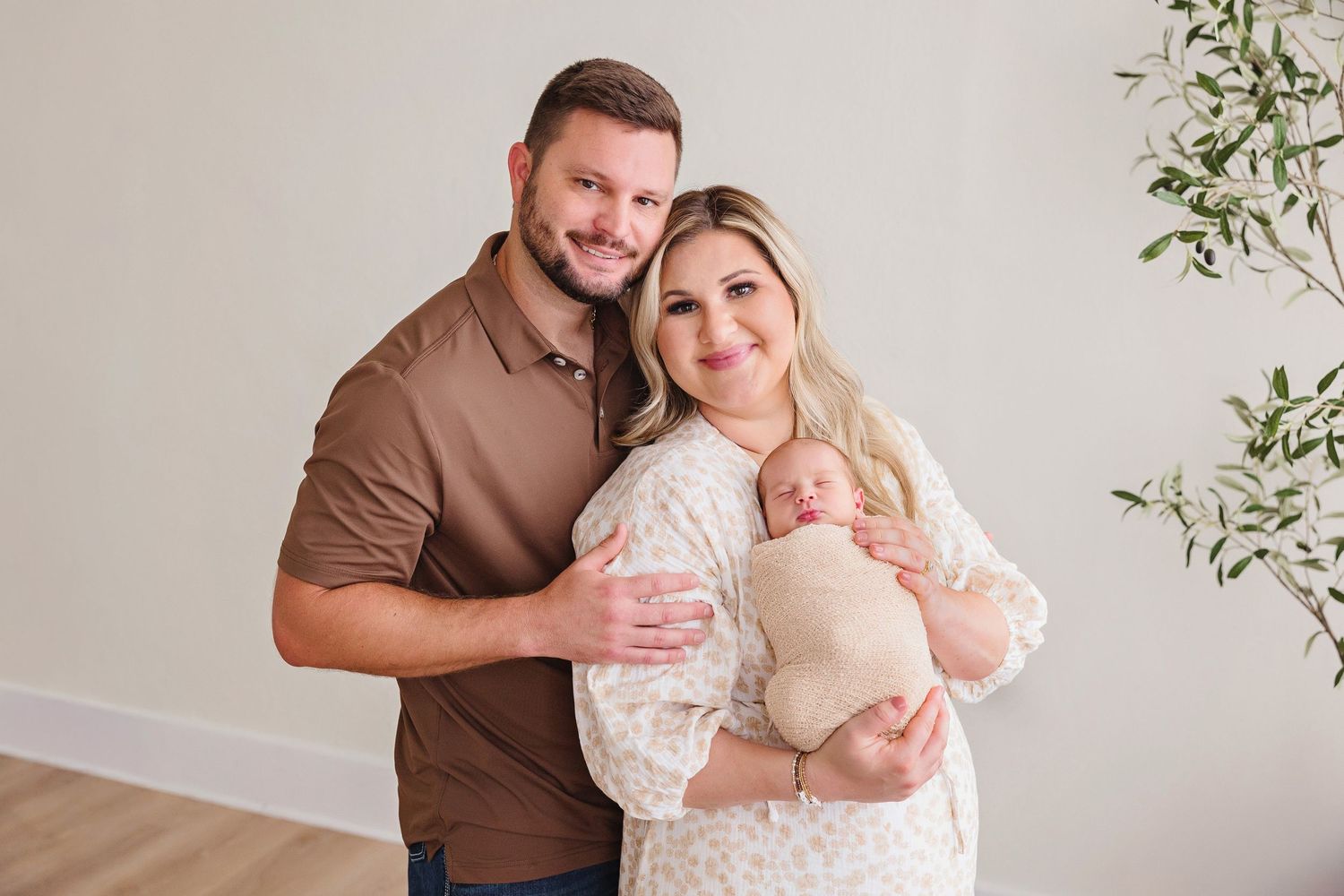 Intimate family portrait session in a bright modern studio with olive tree decor.