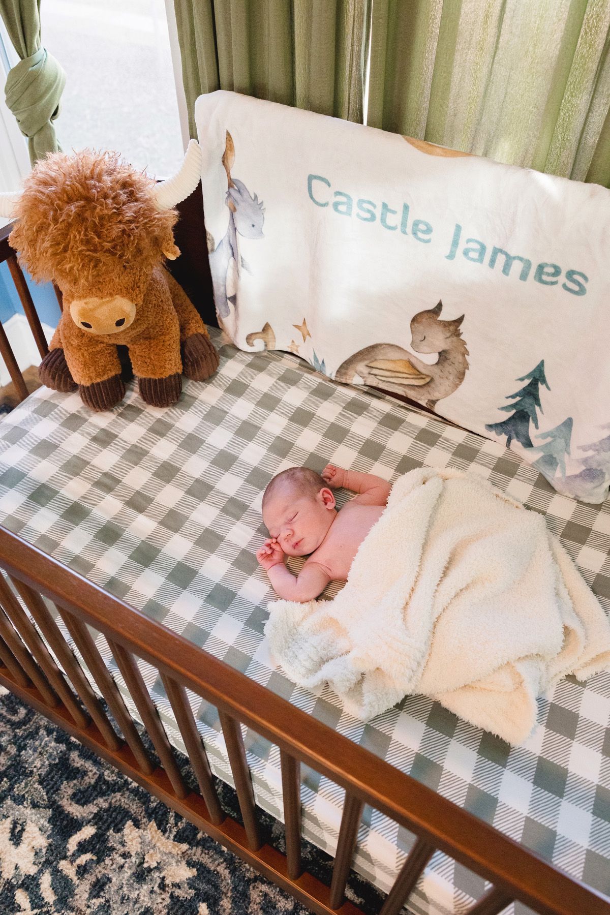 A nursery crib with plaid bedding and stuffed animals displaying woodland-themed decor.