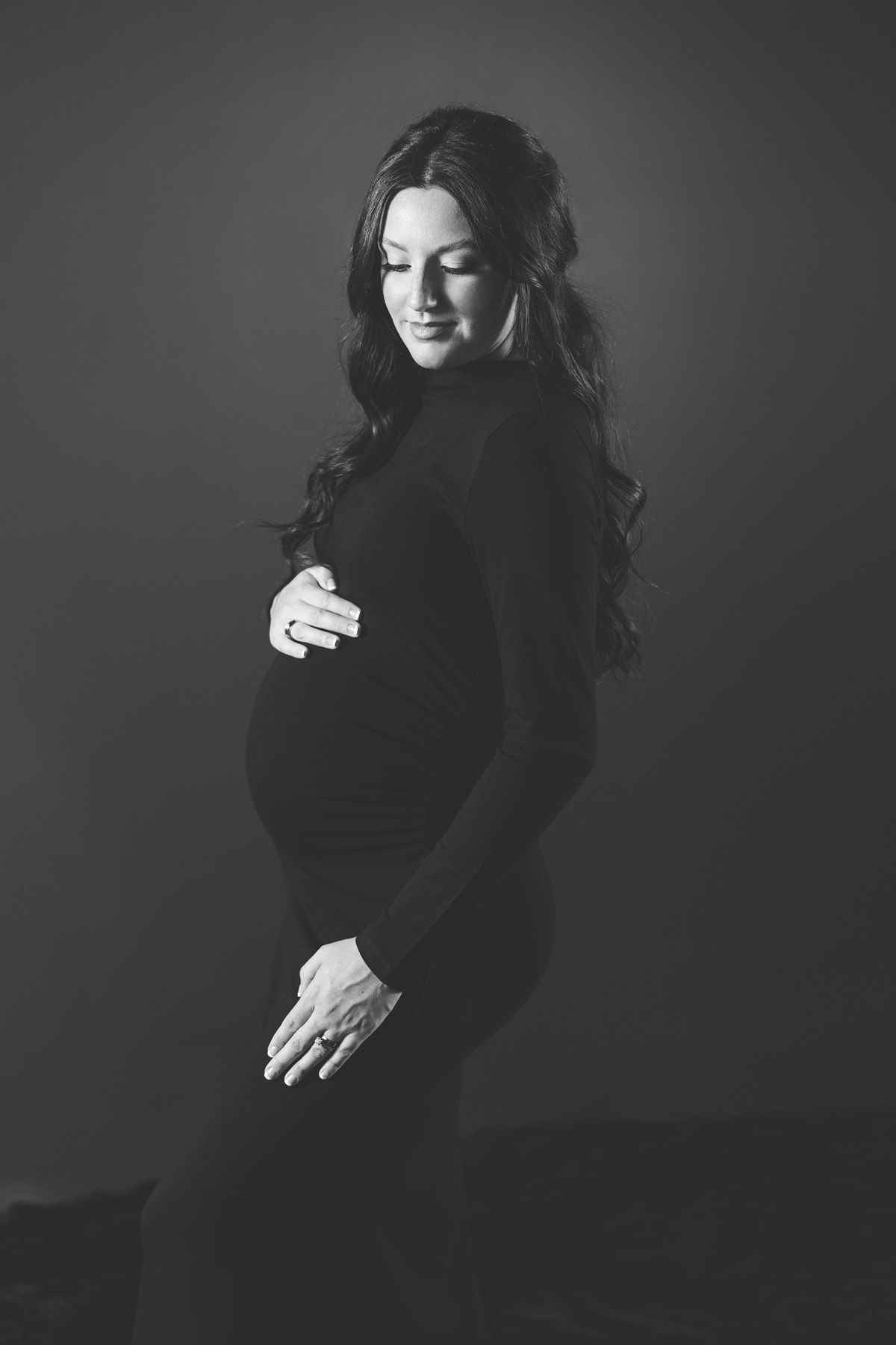 Artistic black and white portrait series showing figure in dark sweater against dark background.
