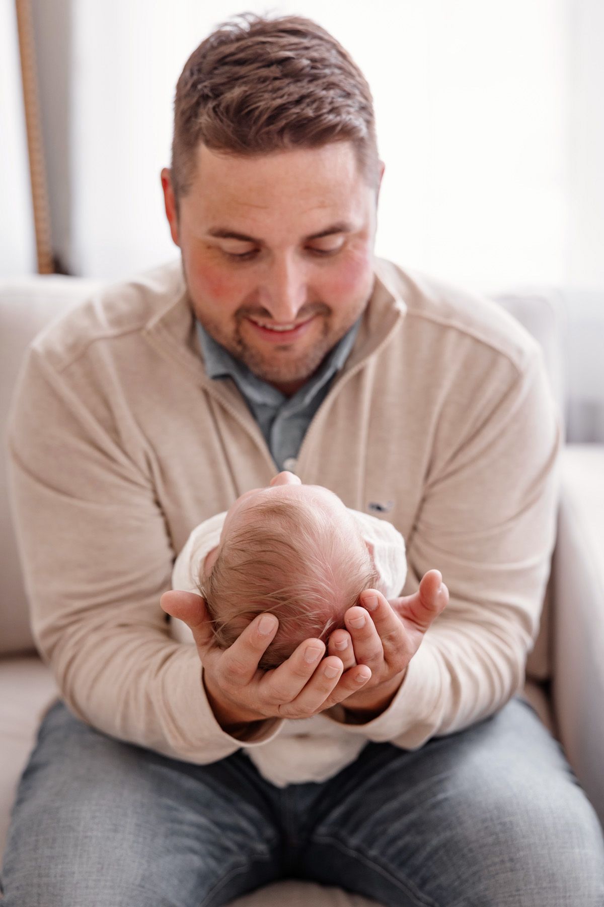 Father holding and bonding with newborn baby in casual home setting.