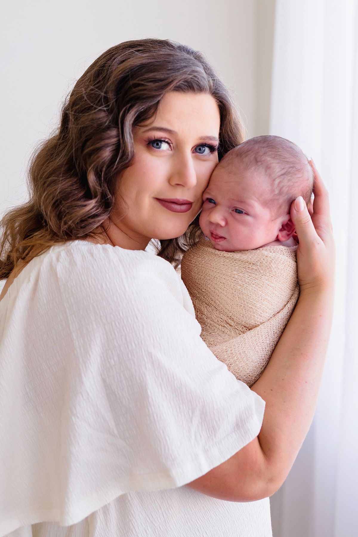Intimate newborn photography session featuring soft white textures and natural lighting.