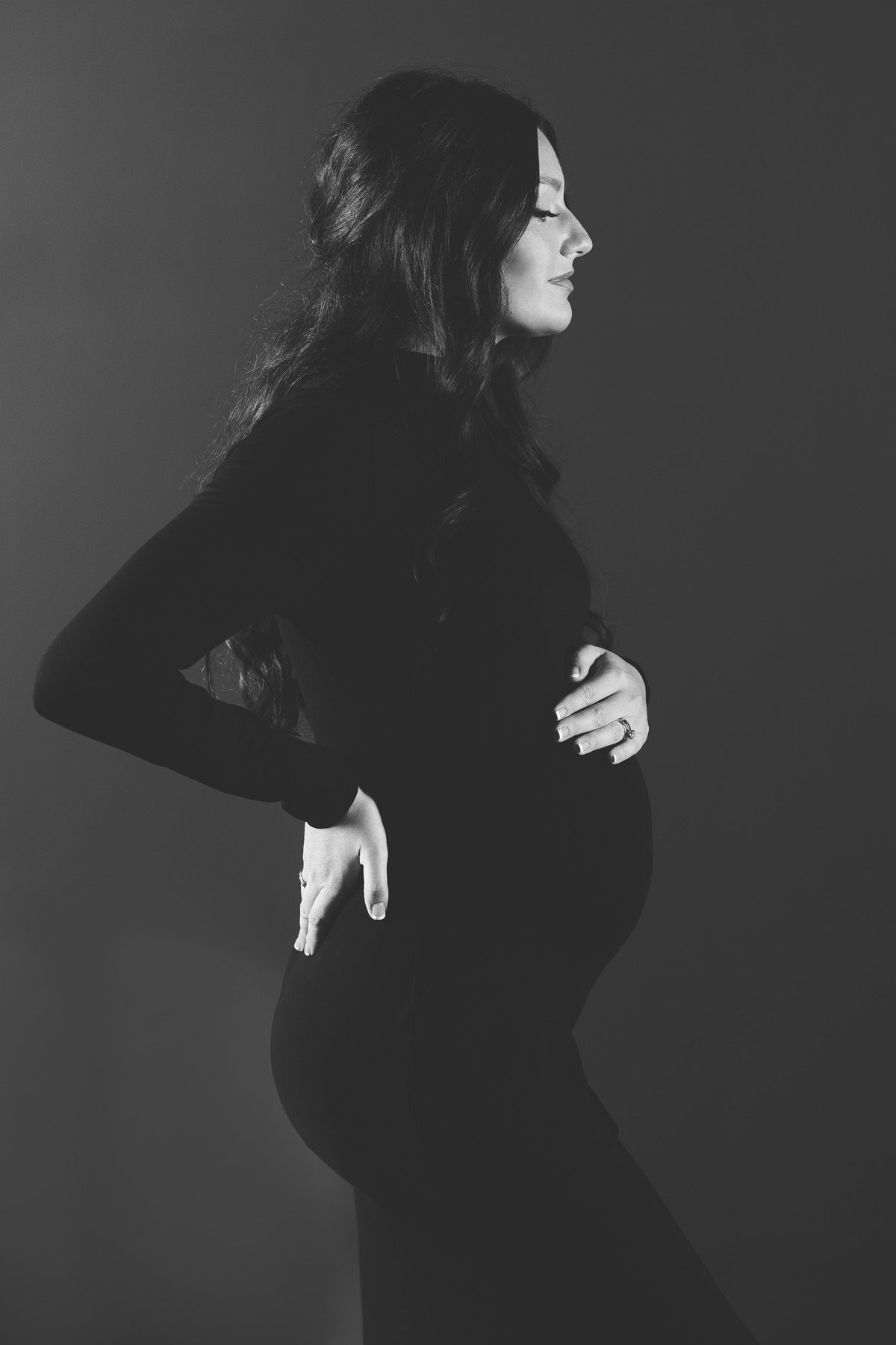 Artistic black and white portrait series showing woman in dark clothing against gray background.