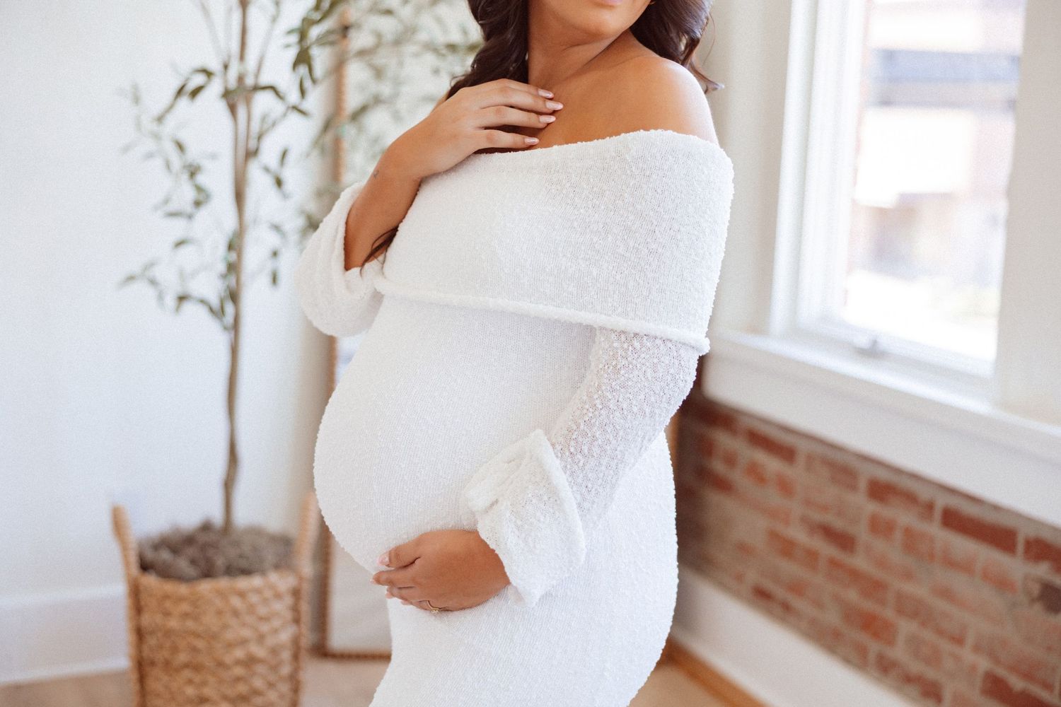 Gentle maternity poses captured in bright indoor setting with white dress.